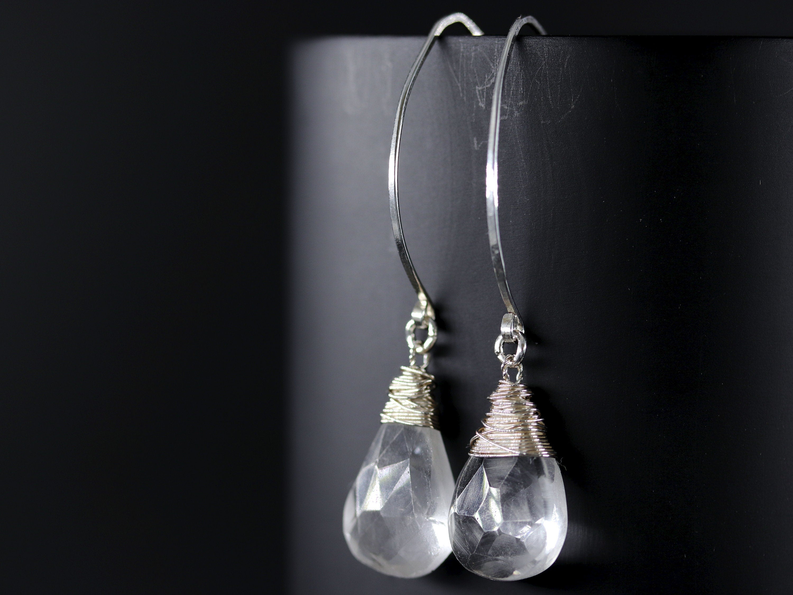 May include: A pair of silver dangle earrings with clear quartz teardrop stones wrapped in silver wire.
