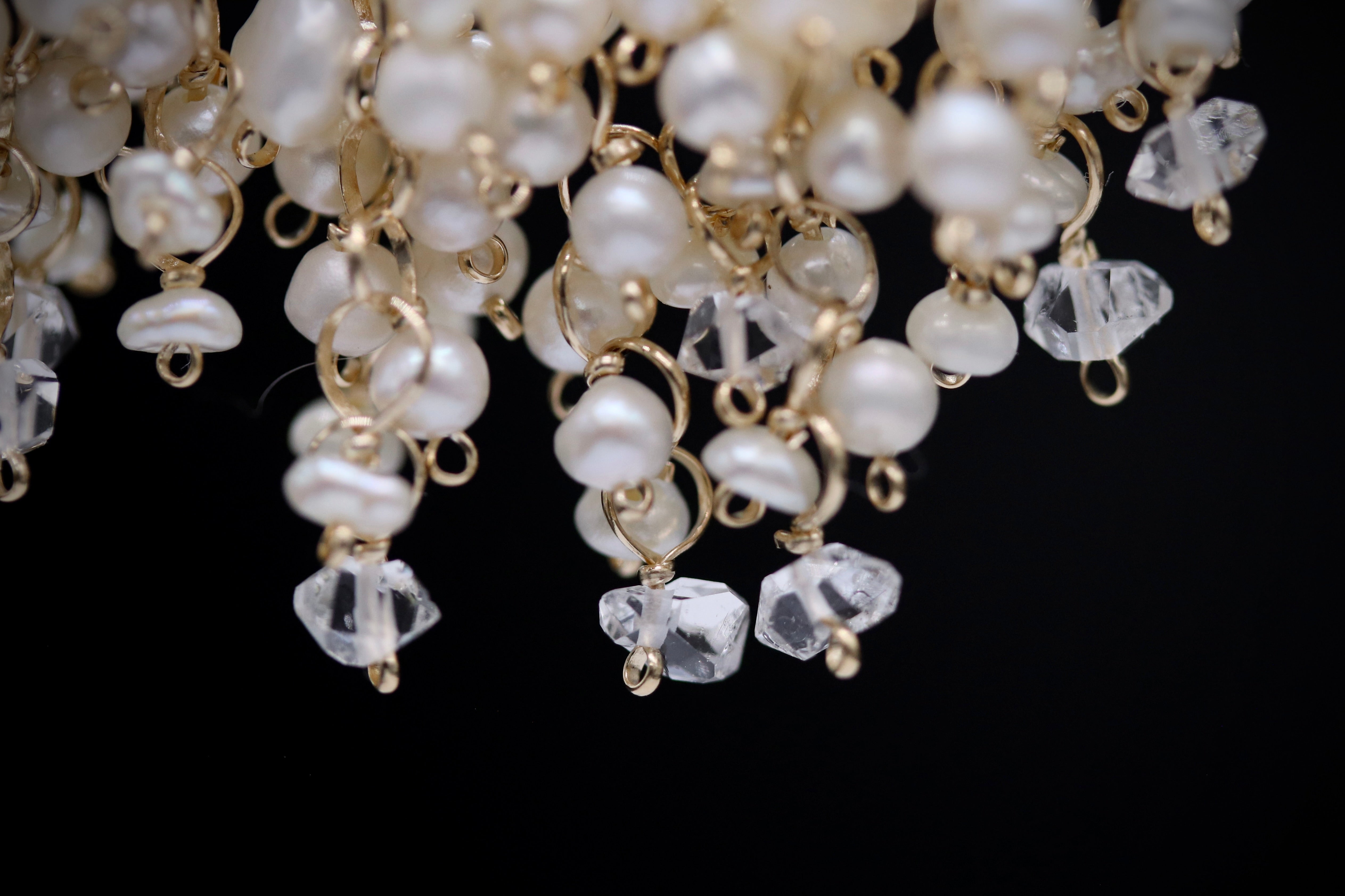 A close-up view of a delicate necklace composed of numerous white pearls and clear gemstones, creating a sparkling and elegant design.