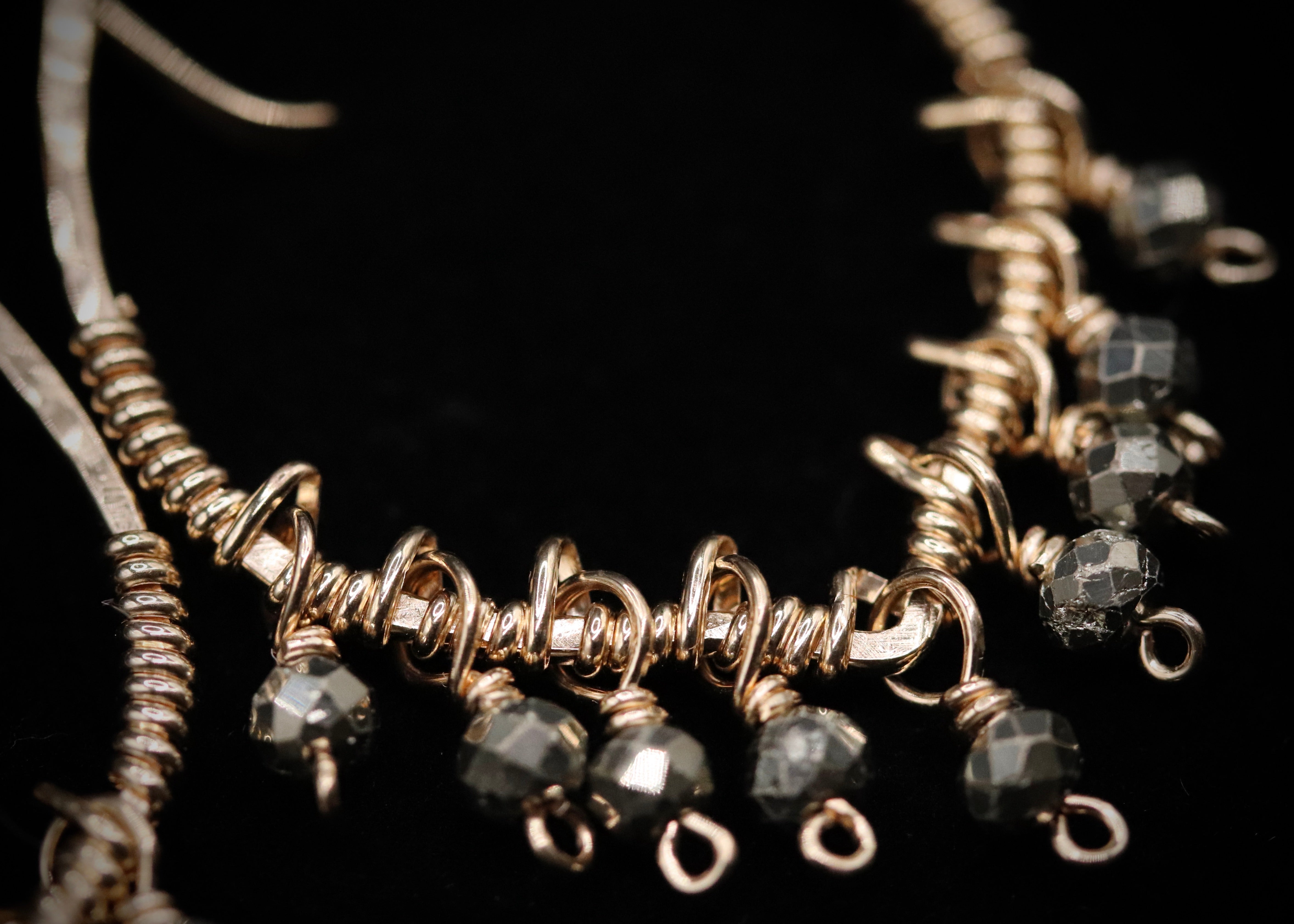 A close-up view of a delicate, ornate necklace with a combination of silver and black beads, showcasing intricate details and craftsmanship.