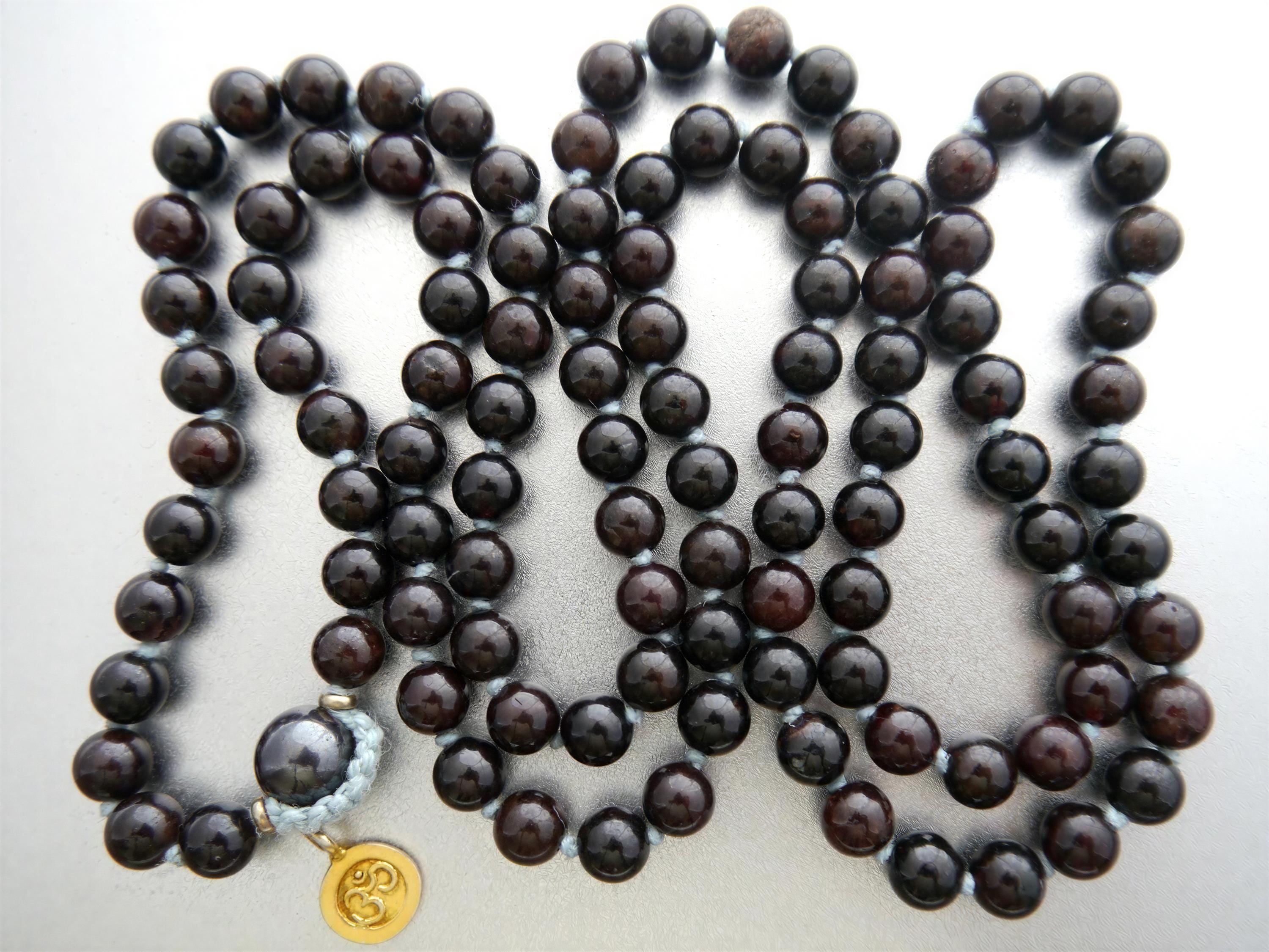 a necklace composed of dark brown beads arranged in a circular pattern, with a gold-colored pendant at the end.