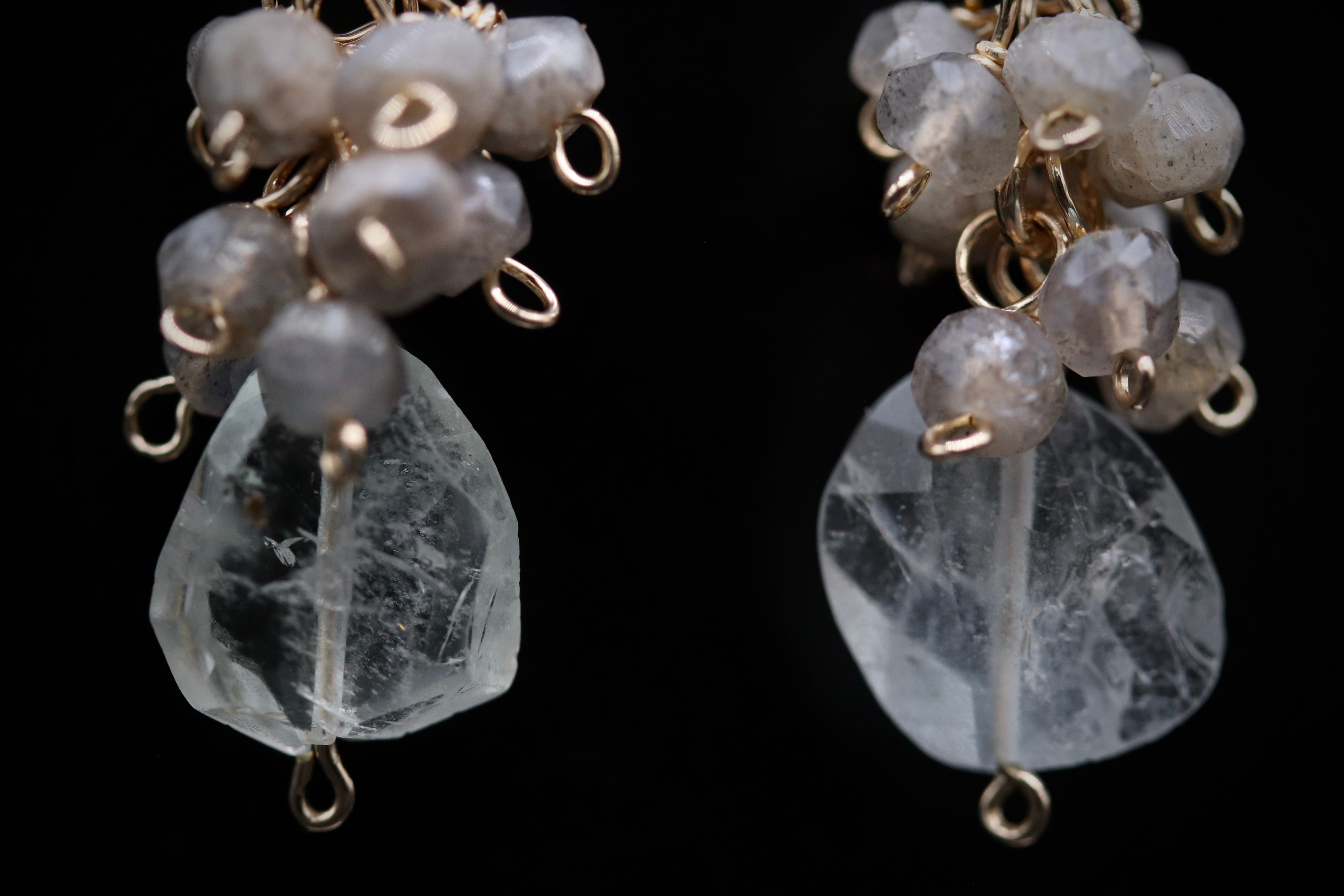 A close-up view of a pair of crystal earrings with clear gemstones and metal chains.