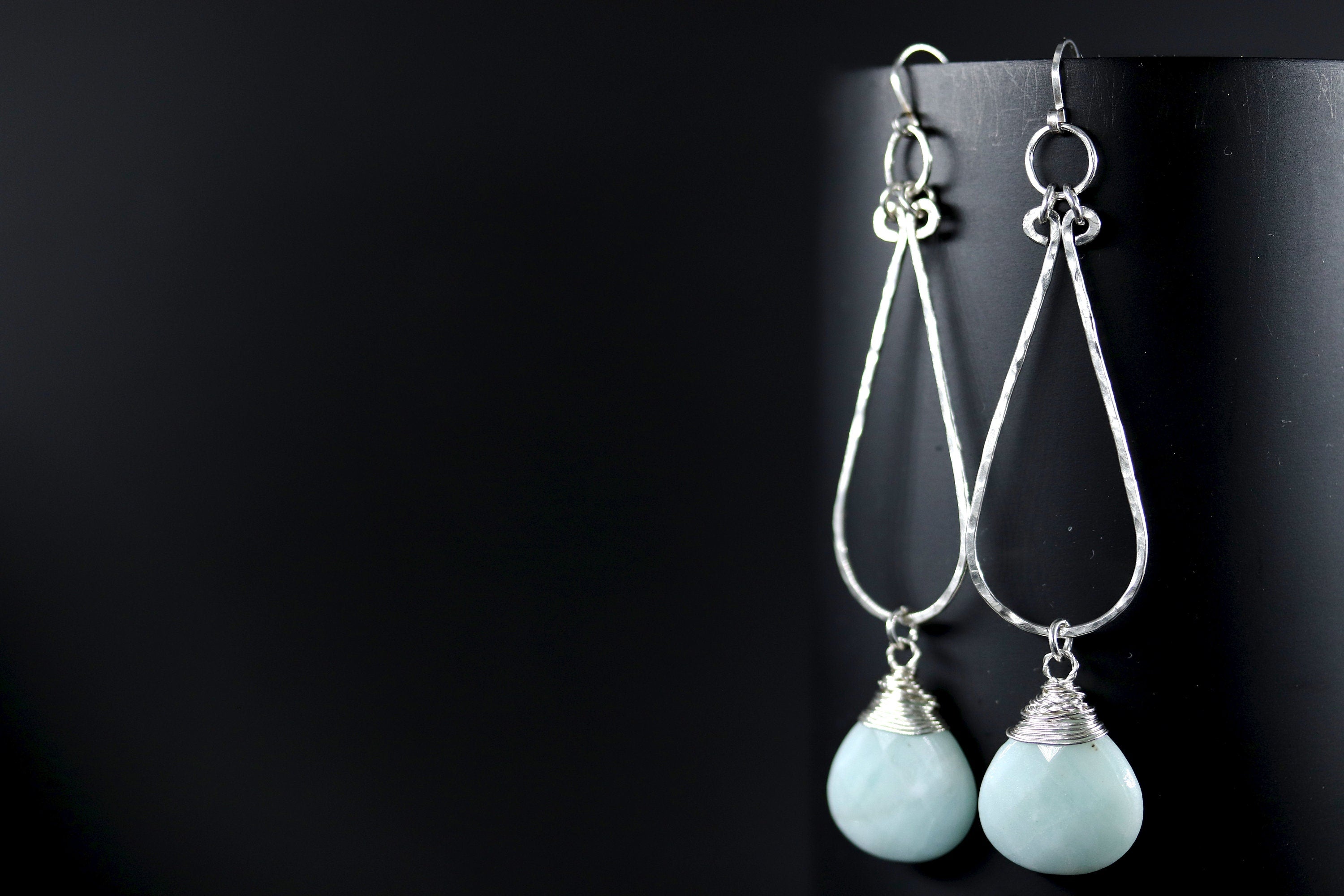 May include: A pair of silver teardrop earrings with light blue gemstone drops.