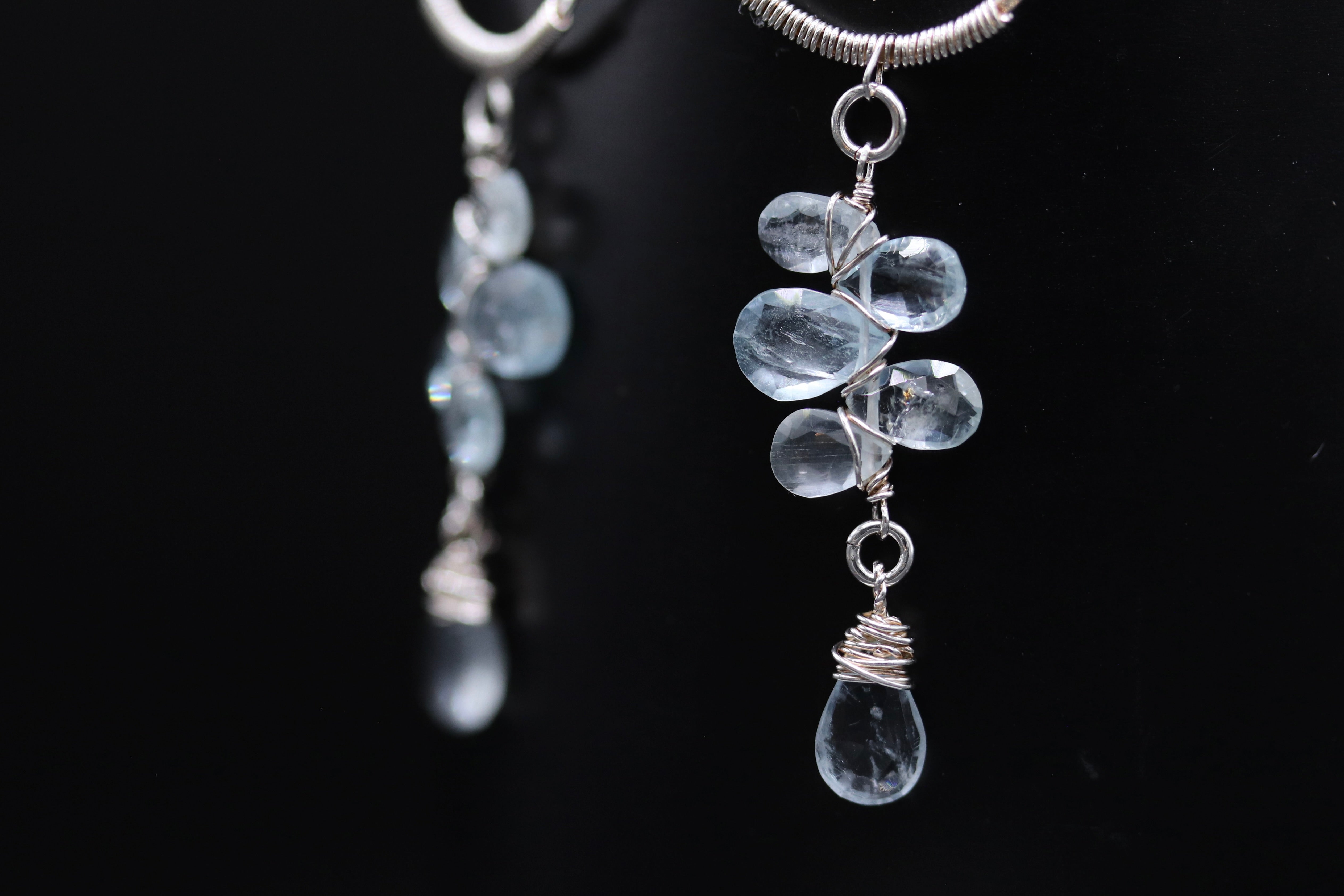 A close-up view of a pair of elegant earrings with clear crystal stones and silver wire.