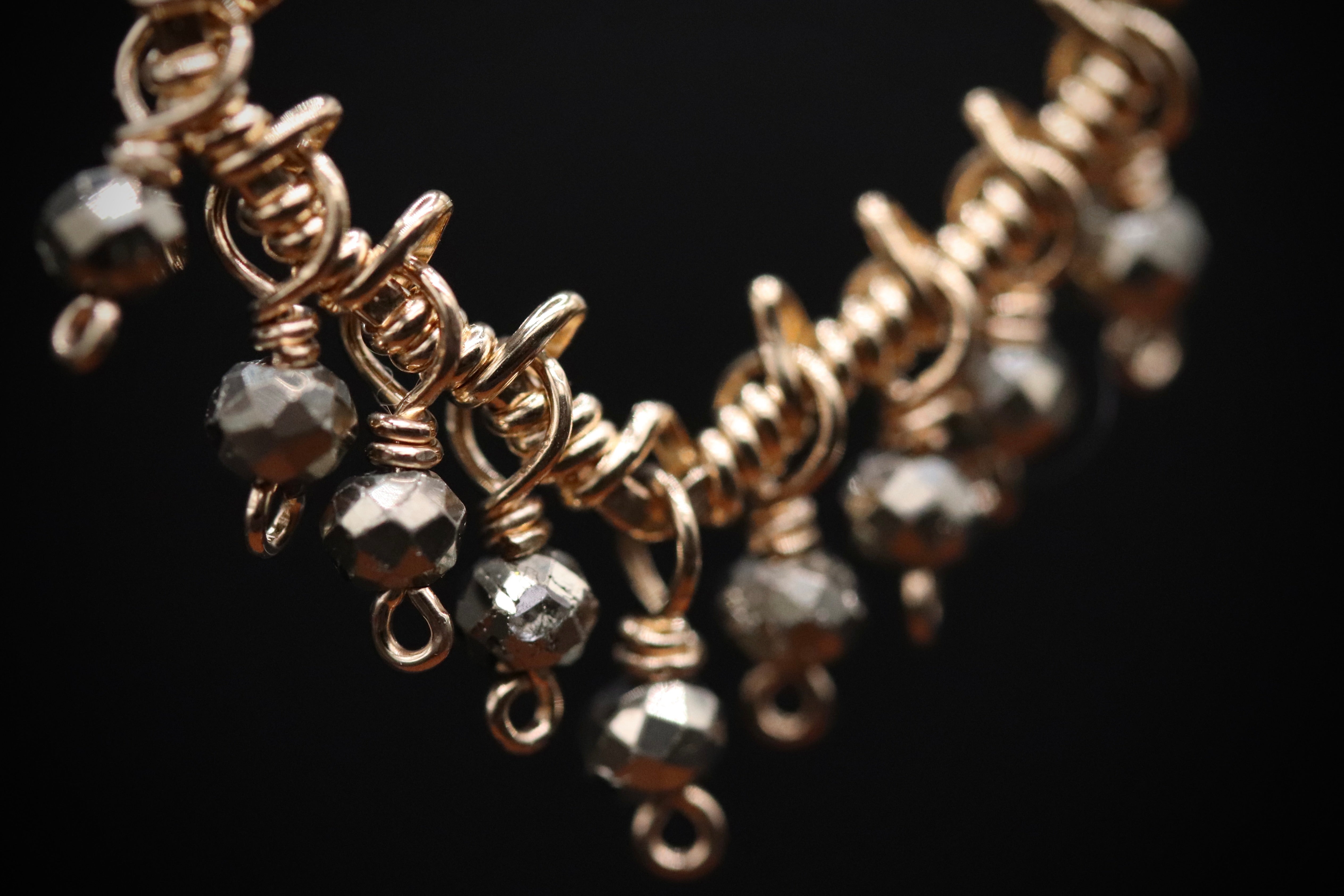 A close-up view of a gold-colored necklace with a series of small, dangling beads and twisted metal components.