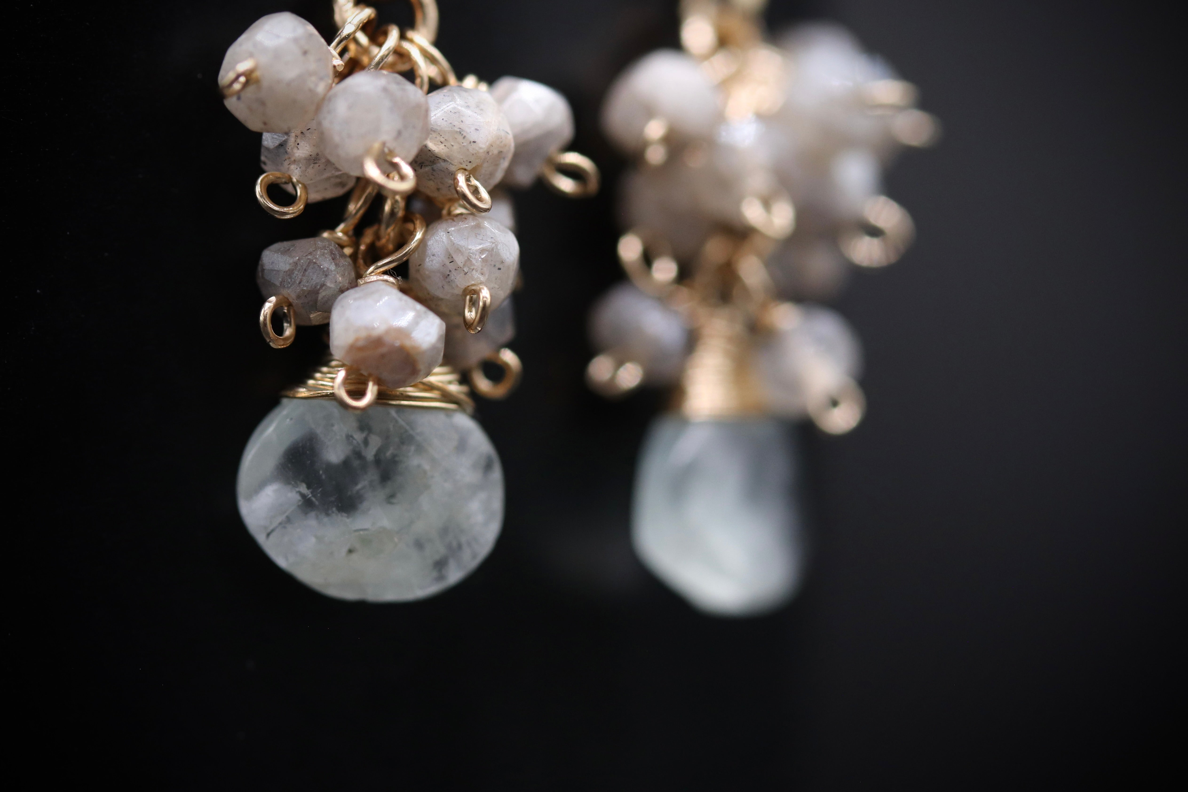 A close-up view of a pair of earrings with white crystal stones and gold-colored metal chains.