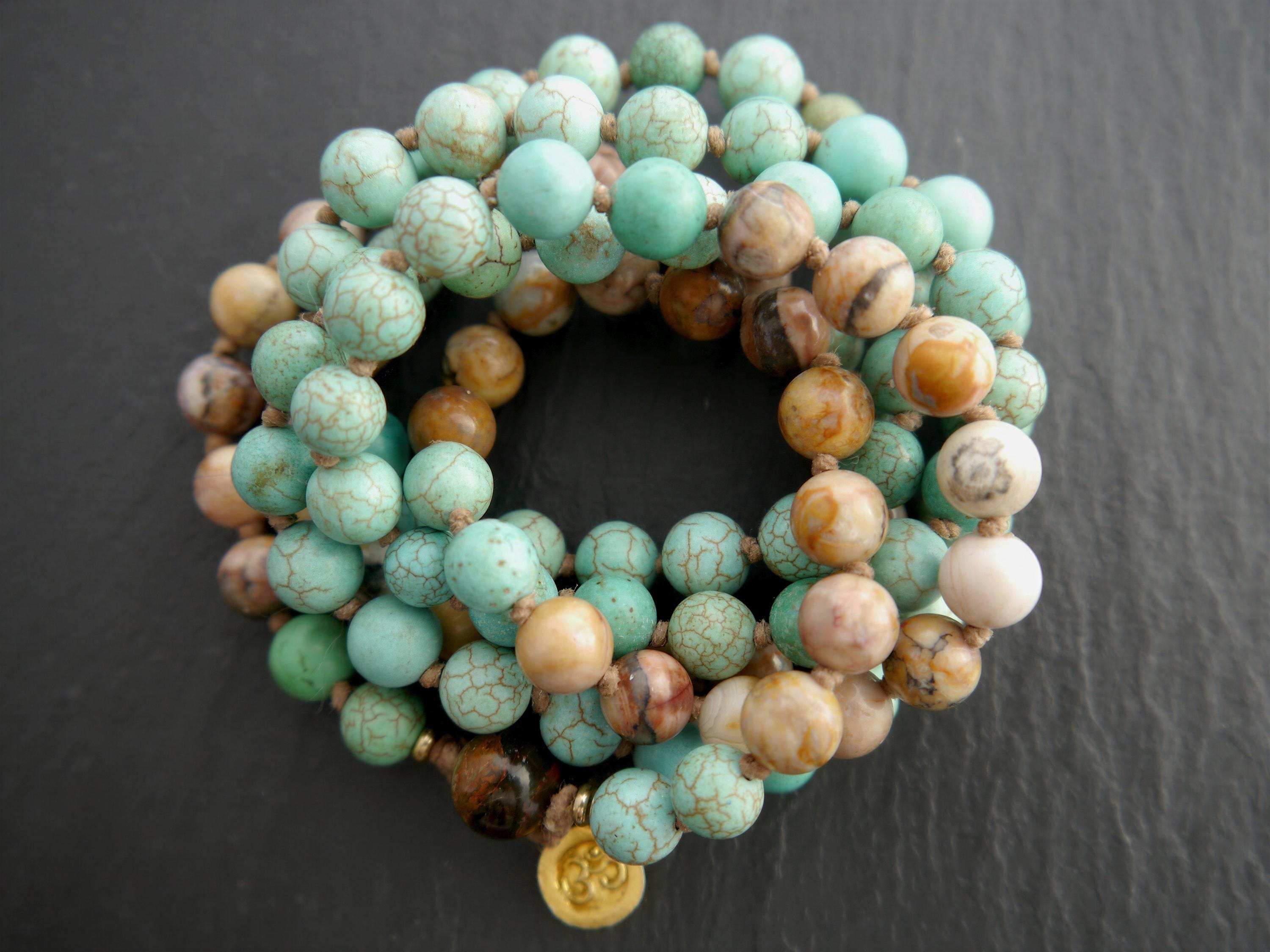 A close-up image of a bracelet made of turquoise and brown beads, with a gold charm attached.
