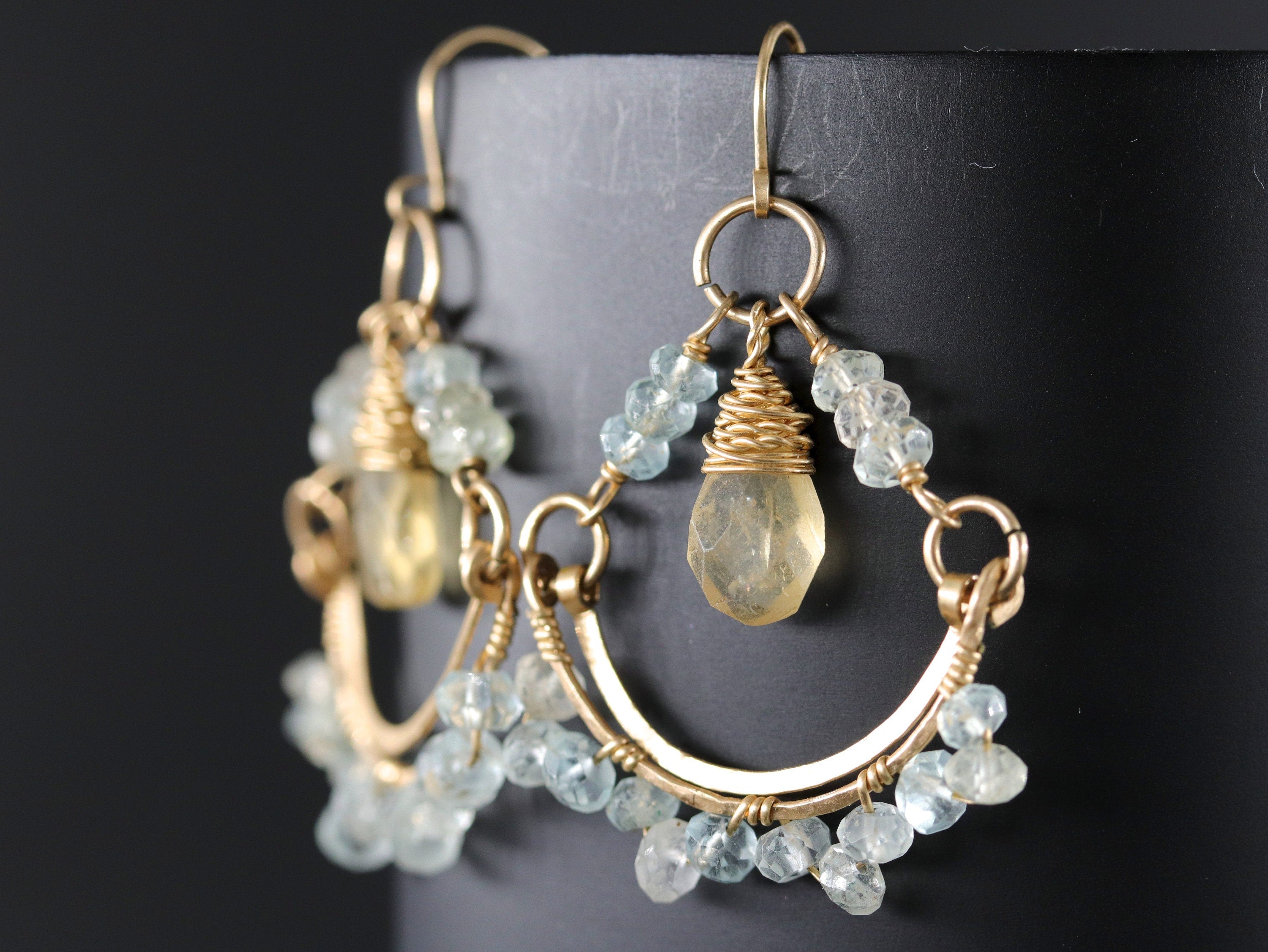 May include: Gold earrings with a teardrop-shaped light yellow gemstone and light blue beads.