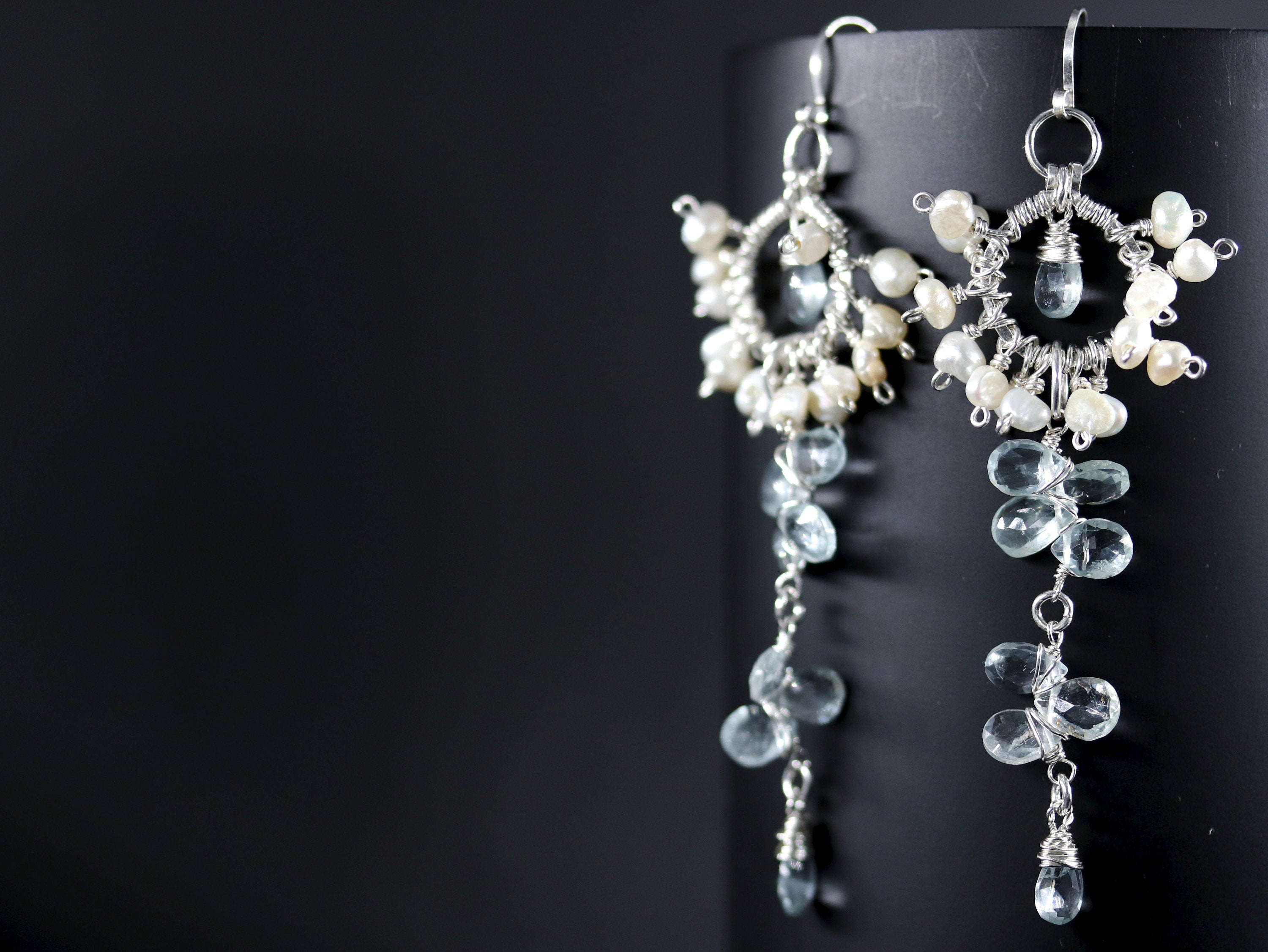 May include: A pair of silver earrings with white pearls and light blue gemstones. The earrings are dangling and have a delicate, intricate design.