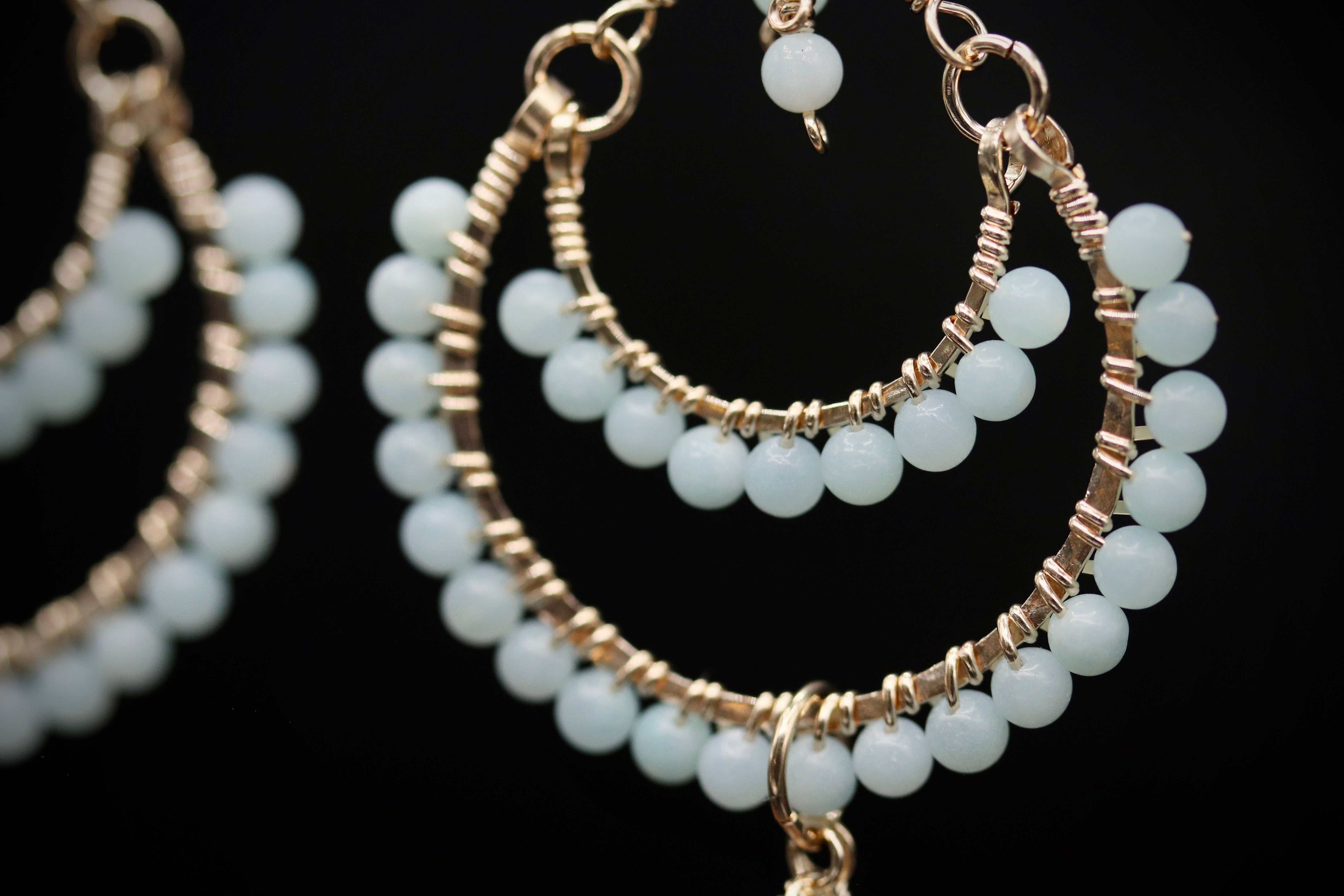 A close-up view of a pair of gold-colored earrings with white beads, showcasing the intricate design and craftsmanship.
