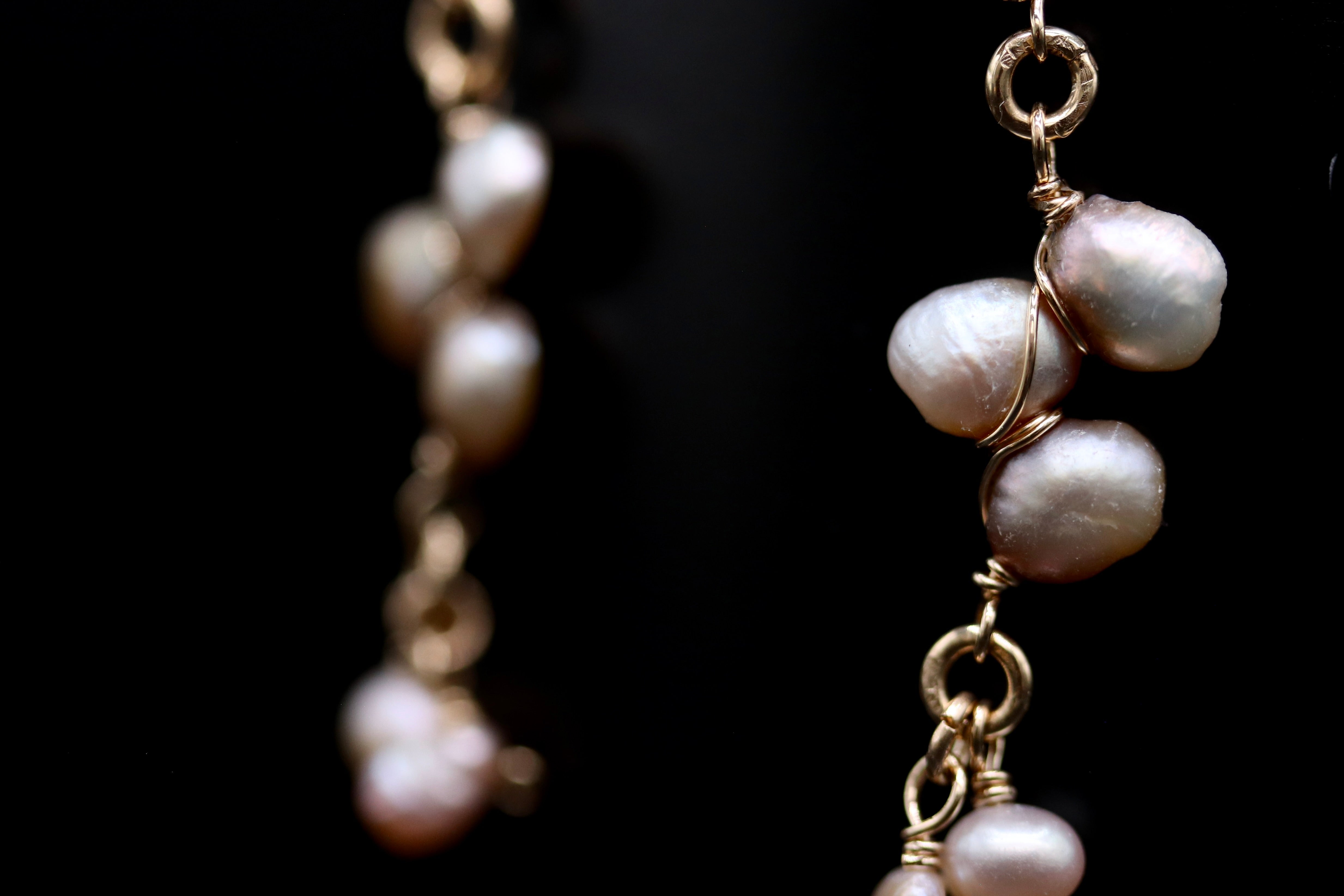 A close-up view of a pair of earrings with multiple pearl-like pendants hanging from a chain.