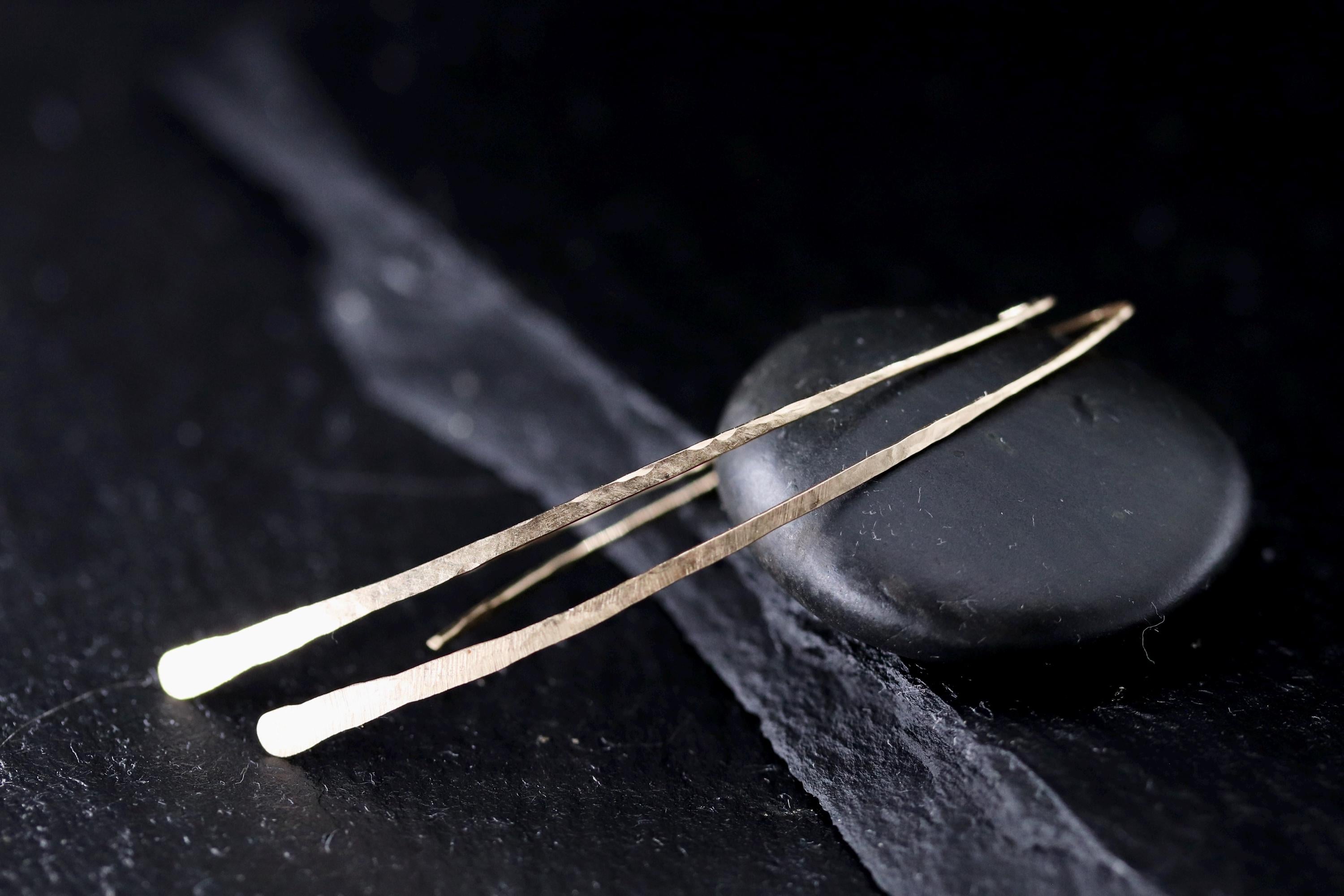 a pair of gold earrings with a dark background, resting on a black surface.