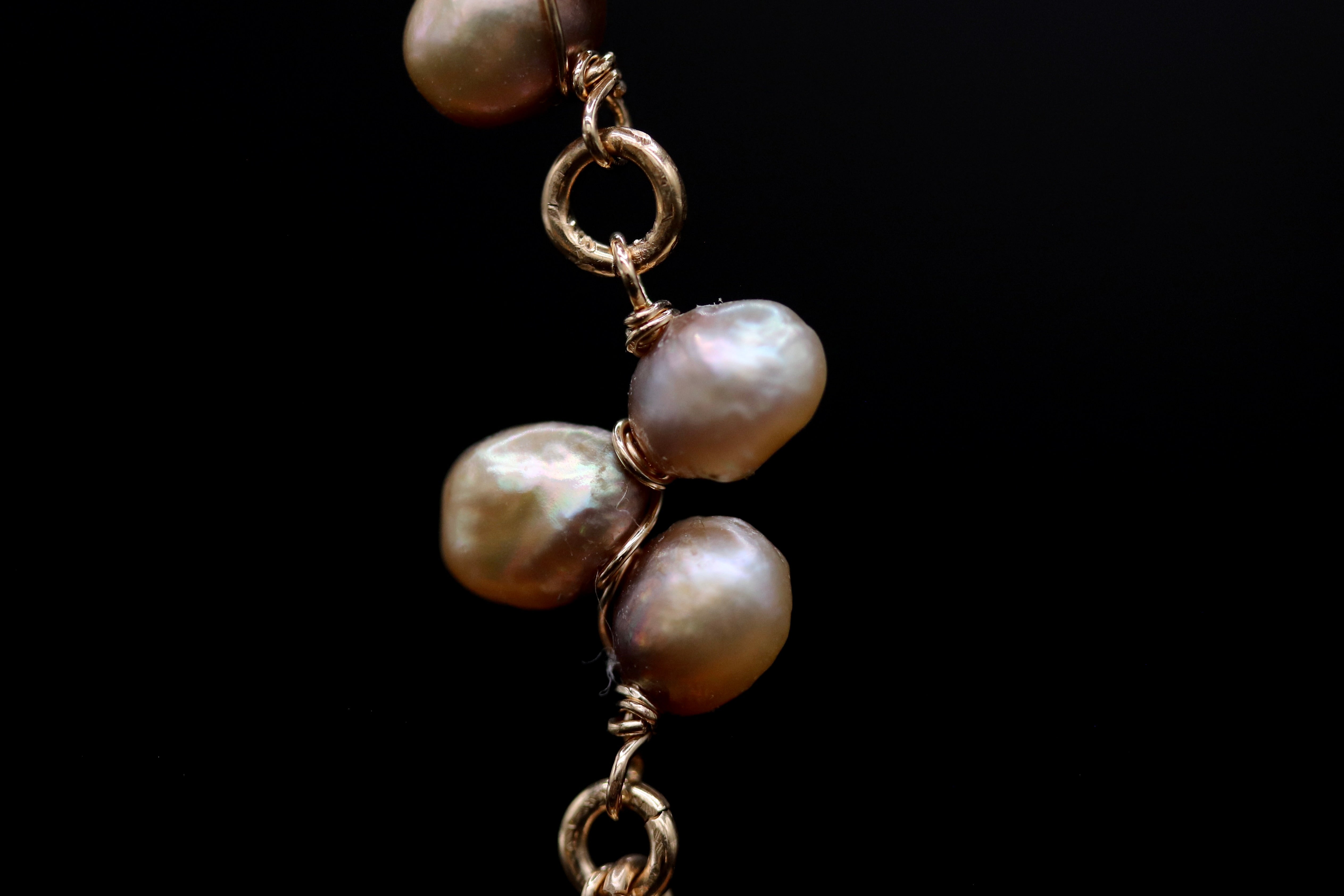 A close-up view of a delicate gold chain with several large, round pearls attached to it.