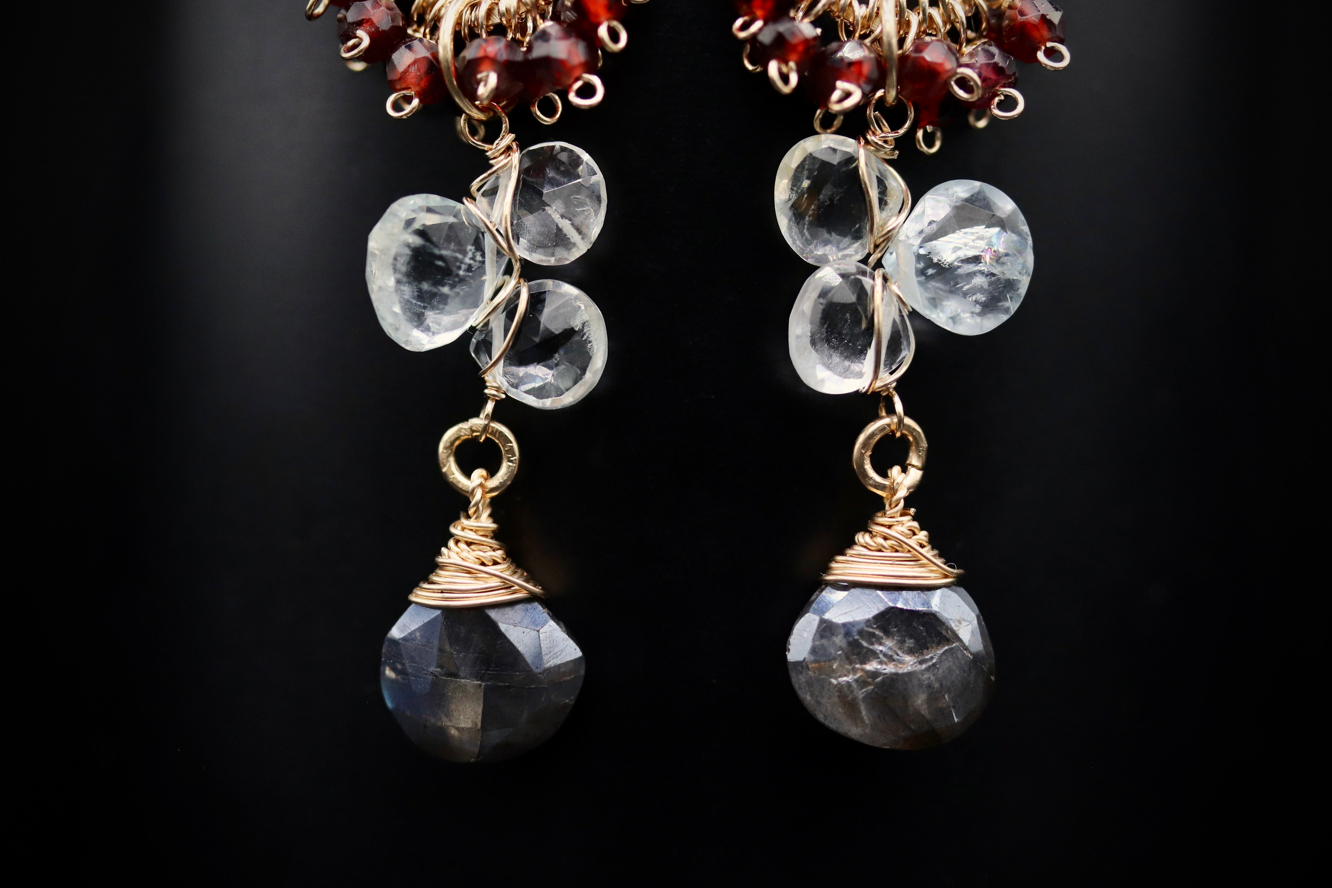 A pair of elegant earrings with clear gemstones and gold-colored metal accents, set against a dark background.