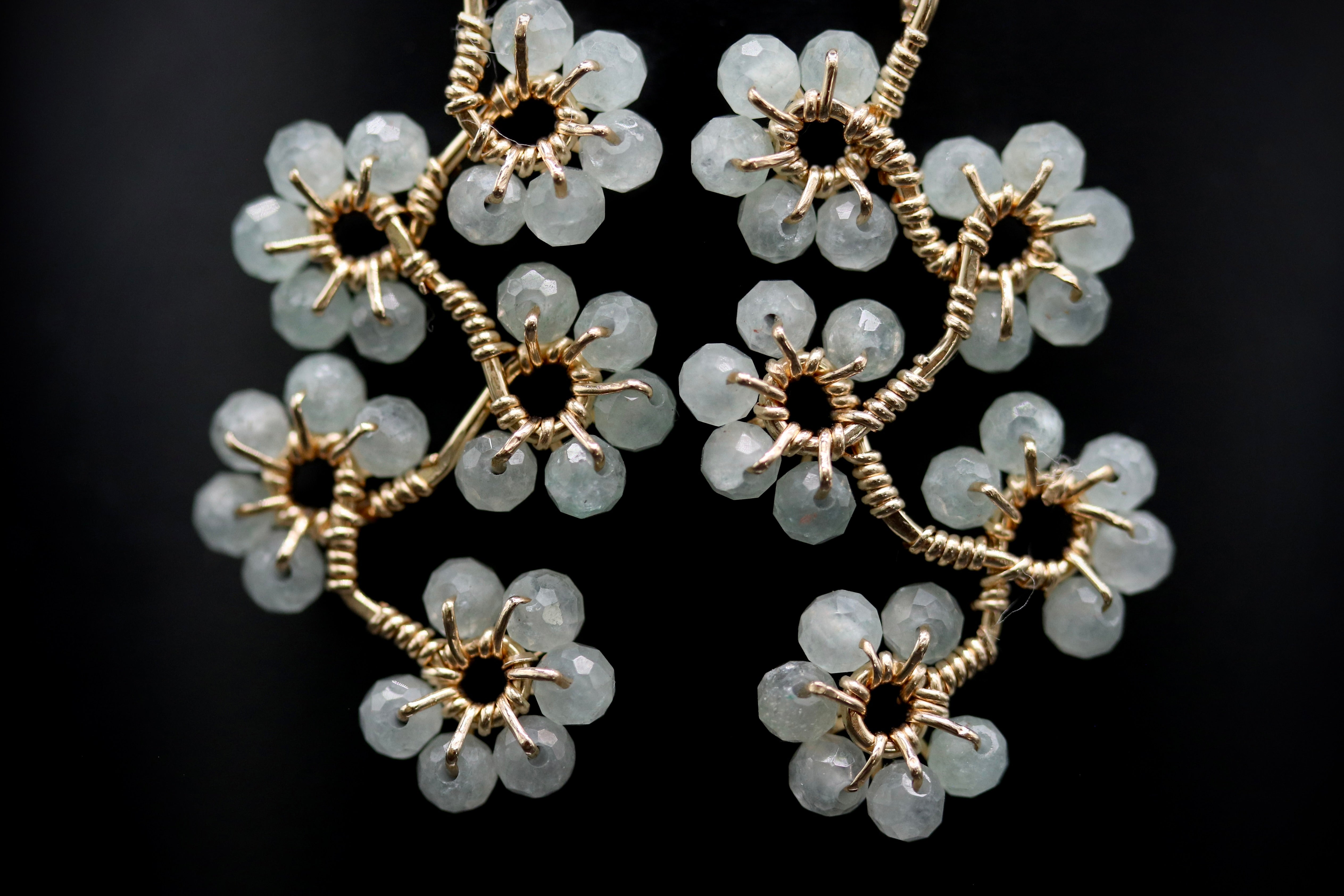 A pair of elegant earrings with delicate white gemstone-like flowers and intricate gold-colored metalwork.
