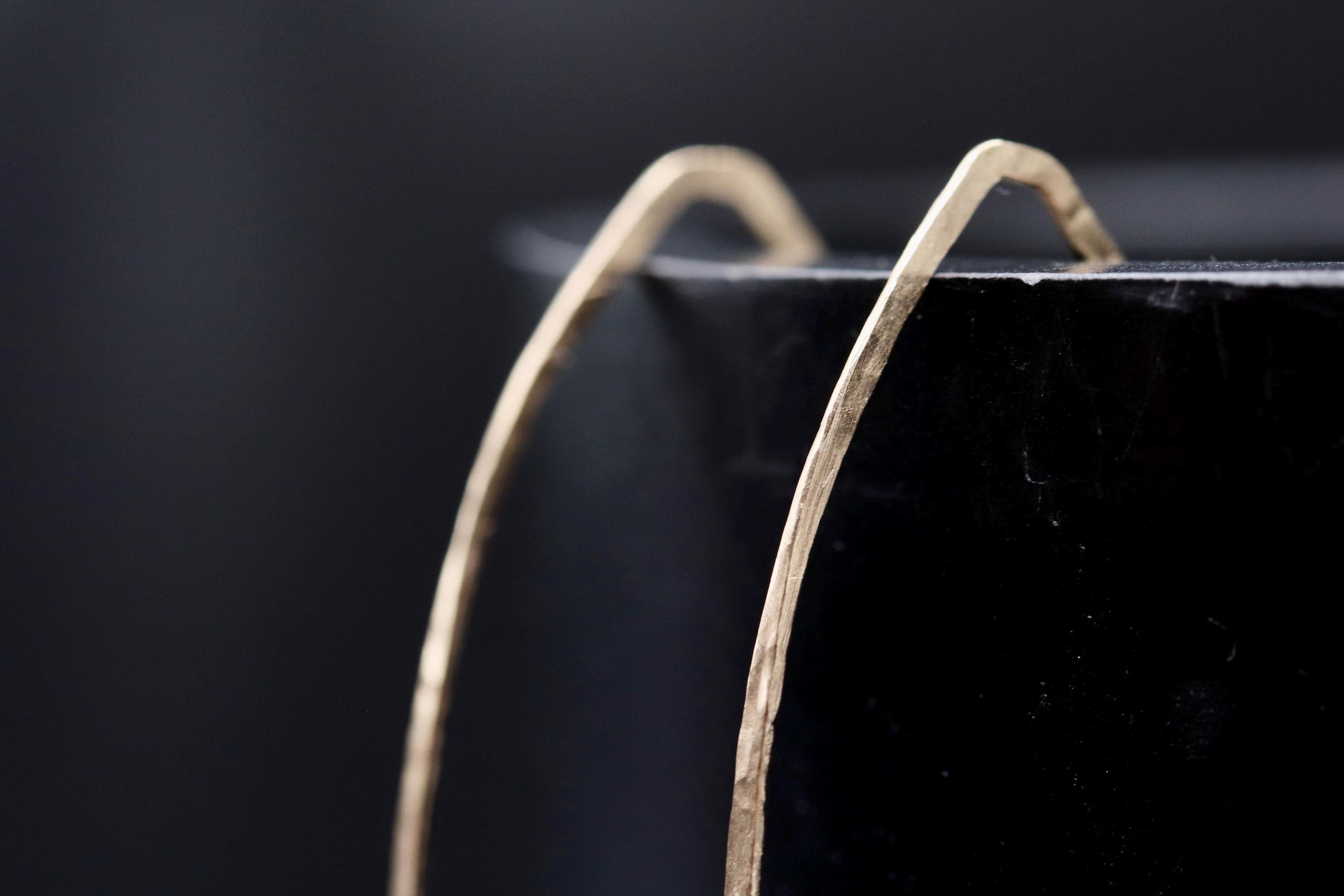 A close-up view of a gold-colored metal object, possibly a piece of jewelry, resting on a black surface.