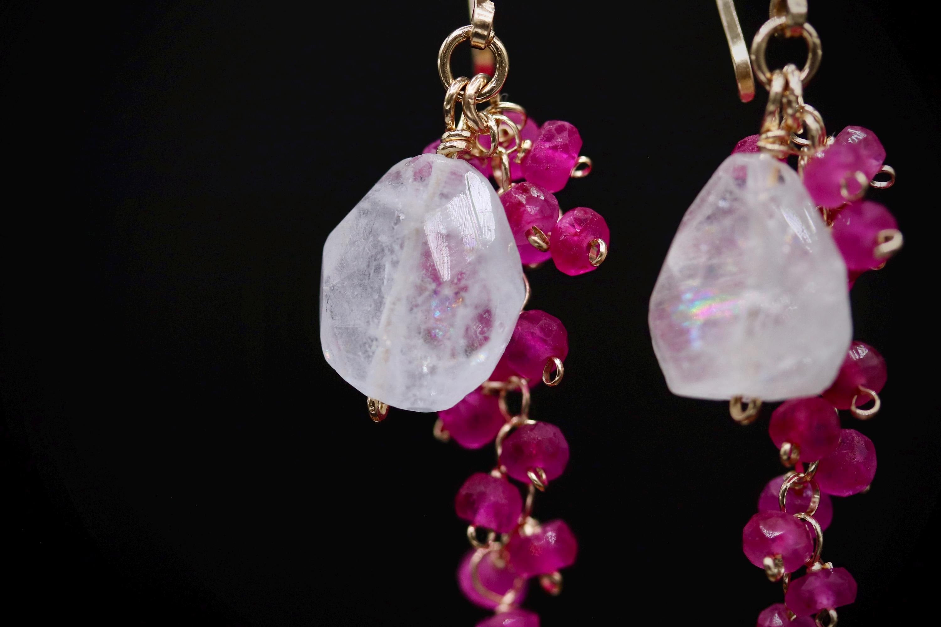 A pair of elegant earrings with a clear gemstone and a cluster of pink beads.
