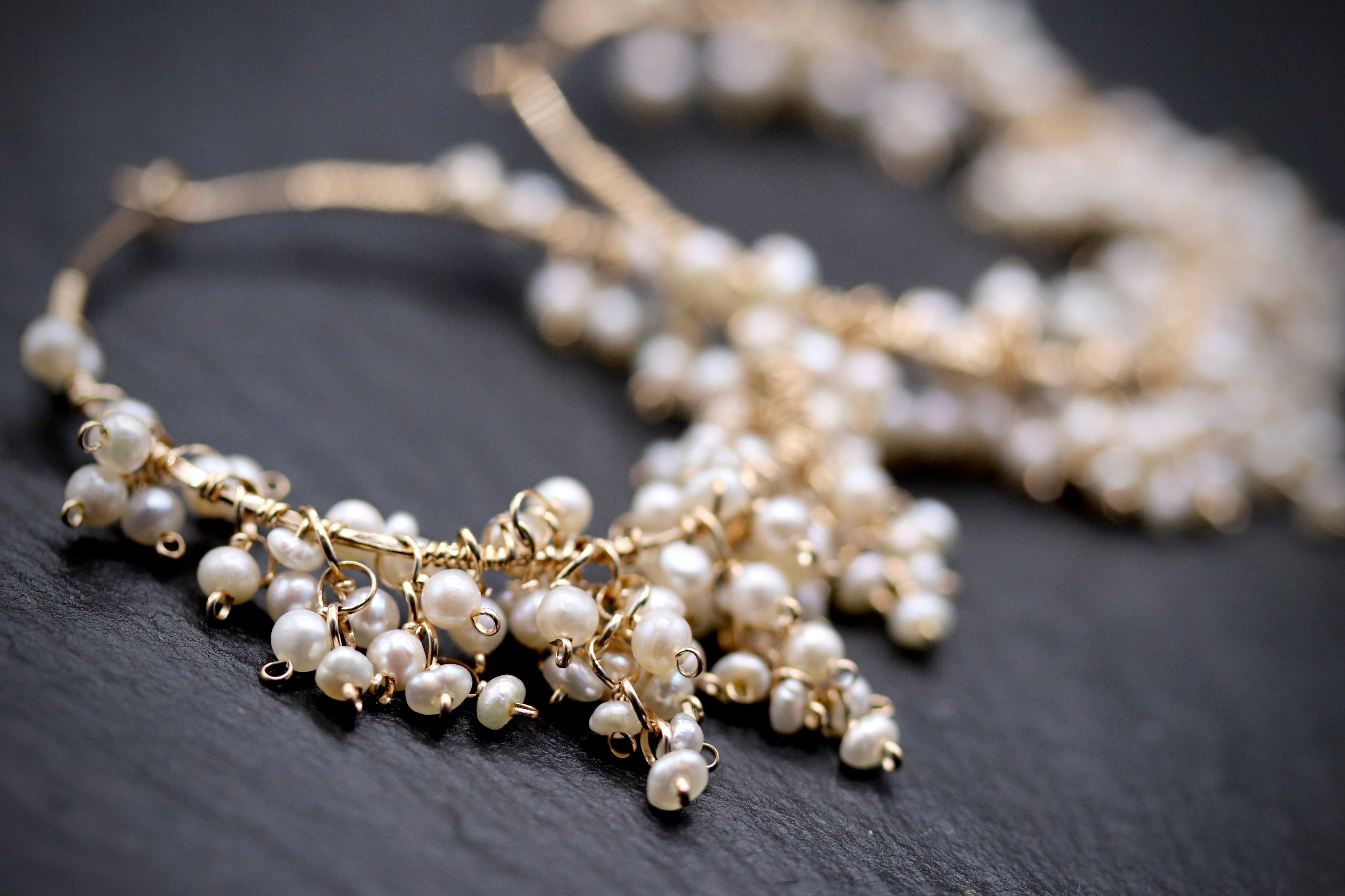 A close-up image of a delicate gold earring adorned with numerous small white pearls.