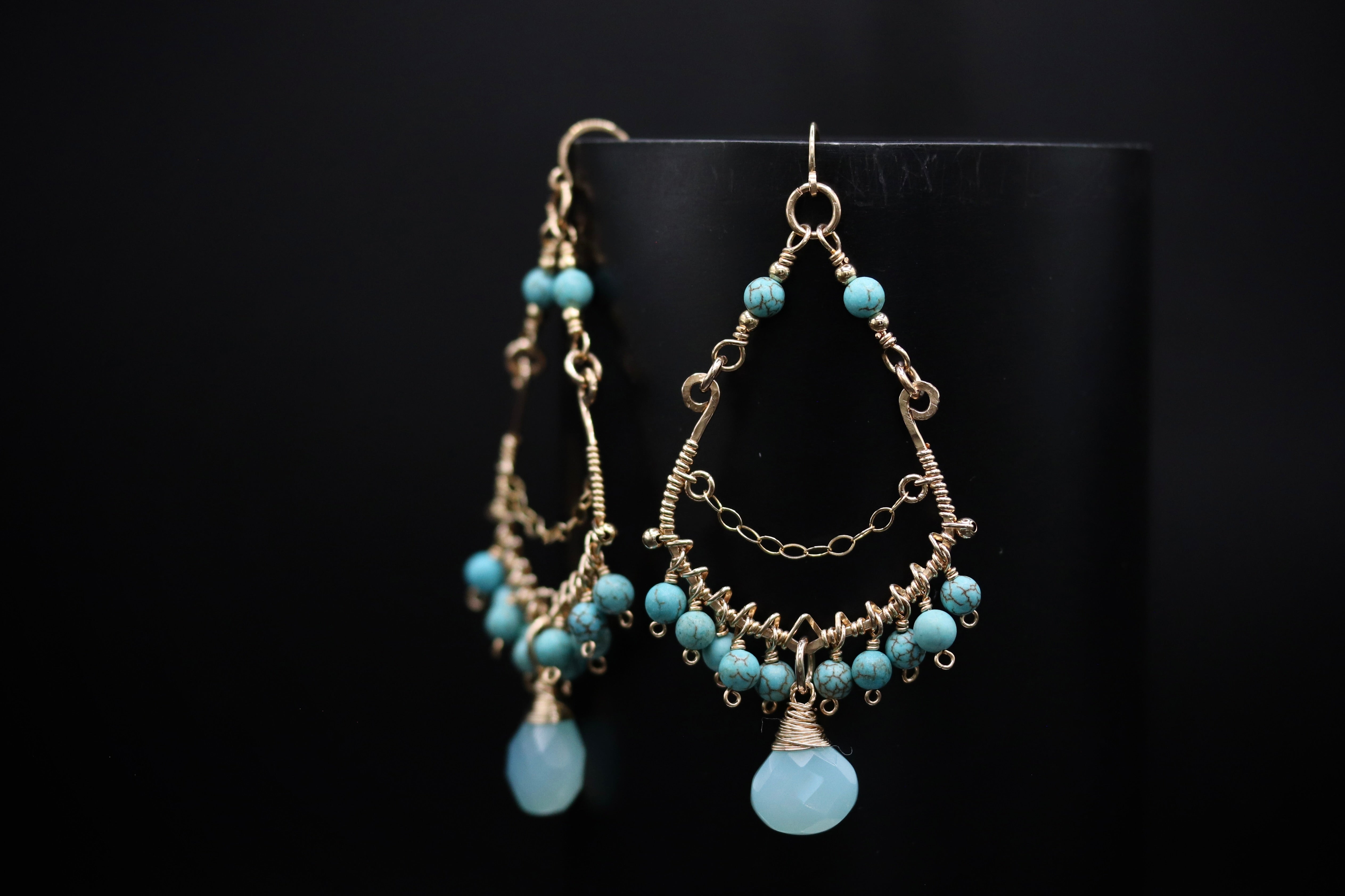 A pair of elegant earrings with turquoise beads and a dangling design, displayed against a black background.
