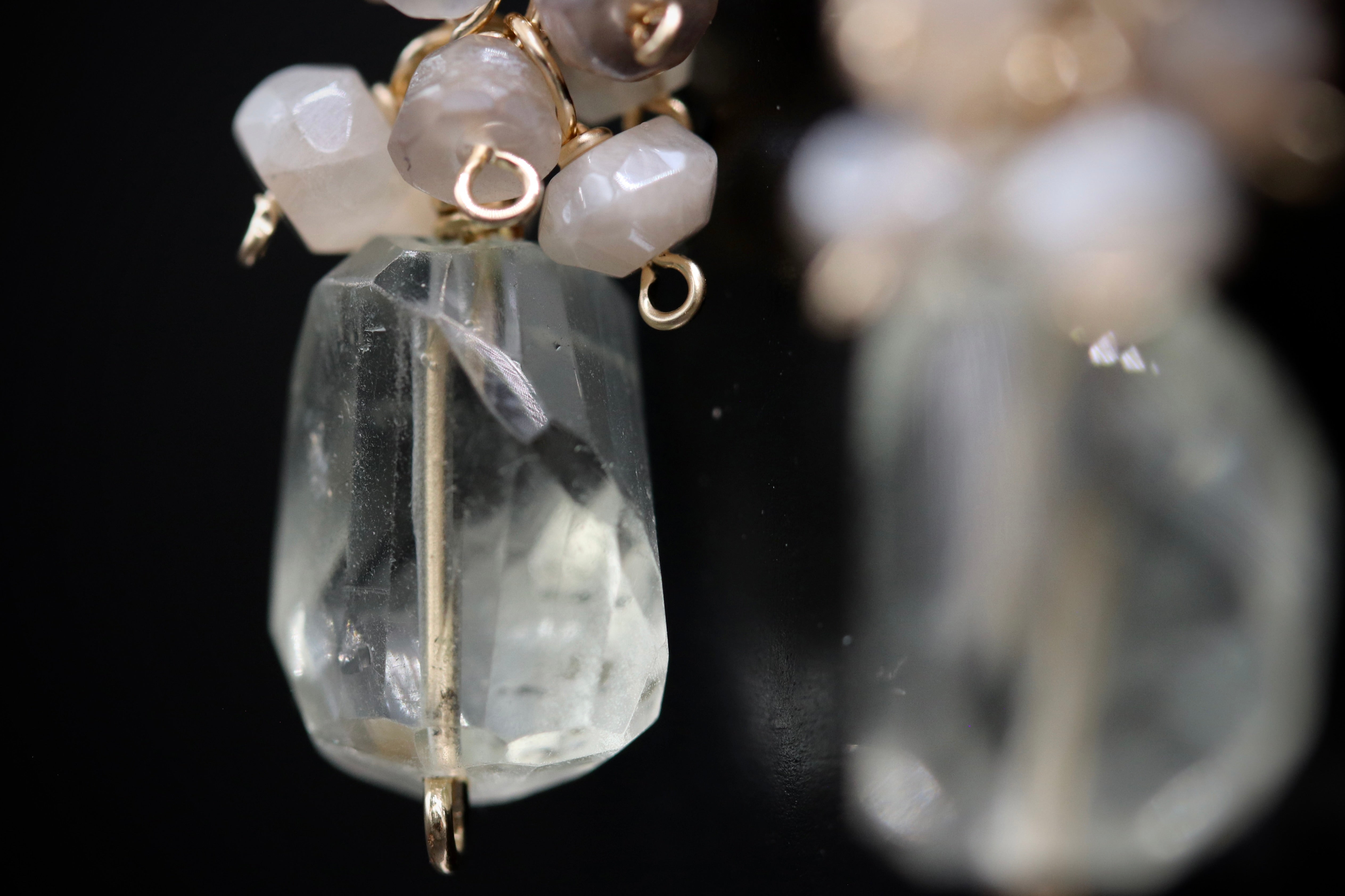 A close-up view of a clear crystal pendant with a gold-colored metal clasp and small white stones.