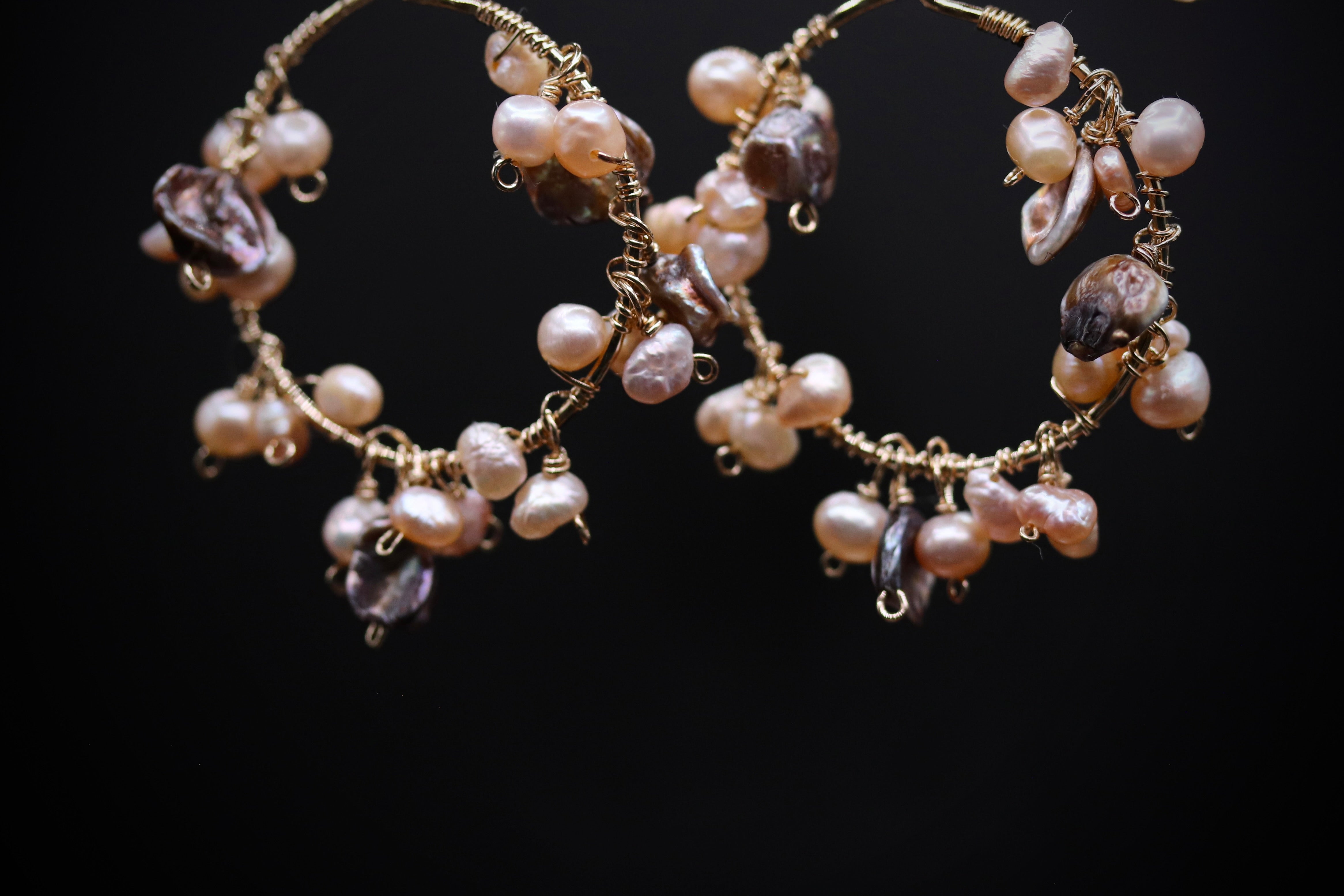 A pair of elegant earrings made of gold wire and adorned with numerous small pearls and beads, creating a delicate and intricate design.