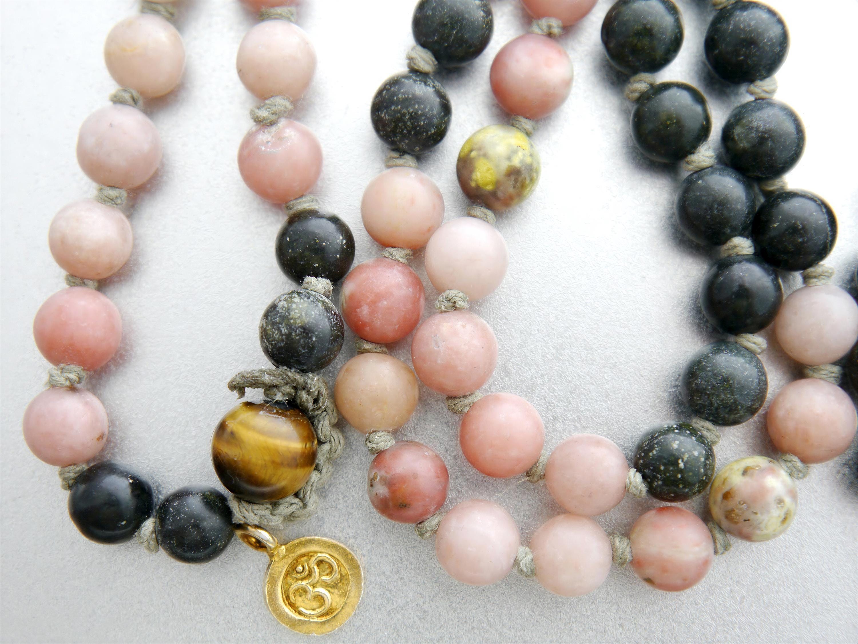 A necklace with various colored beads, including pink, black, and yellow beads, as well as a gold pendant.
