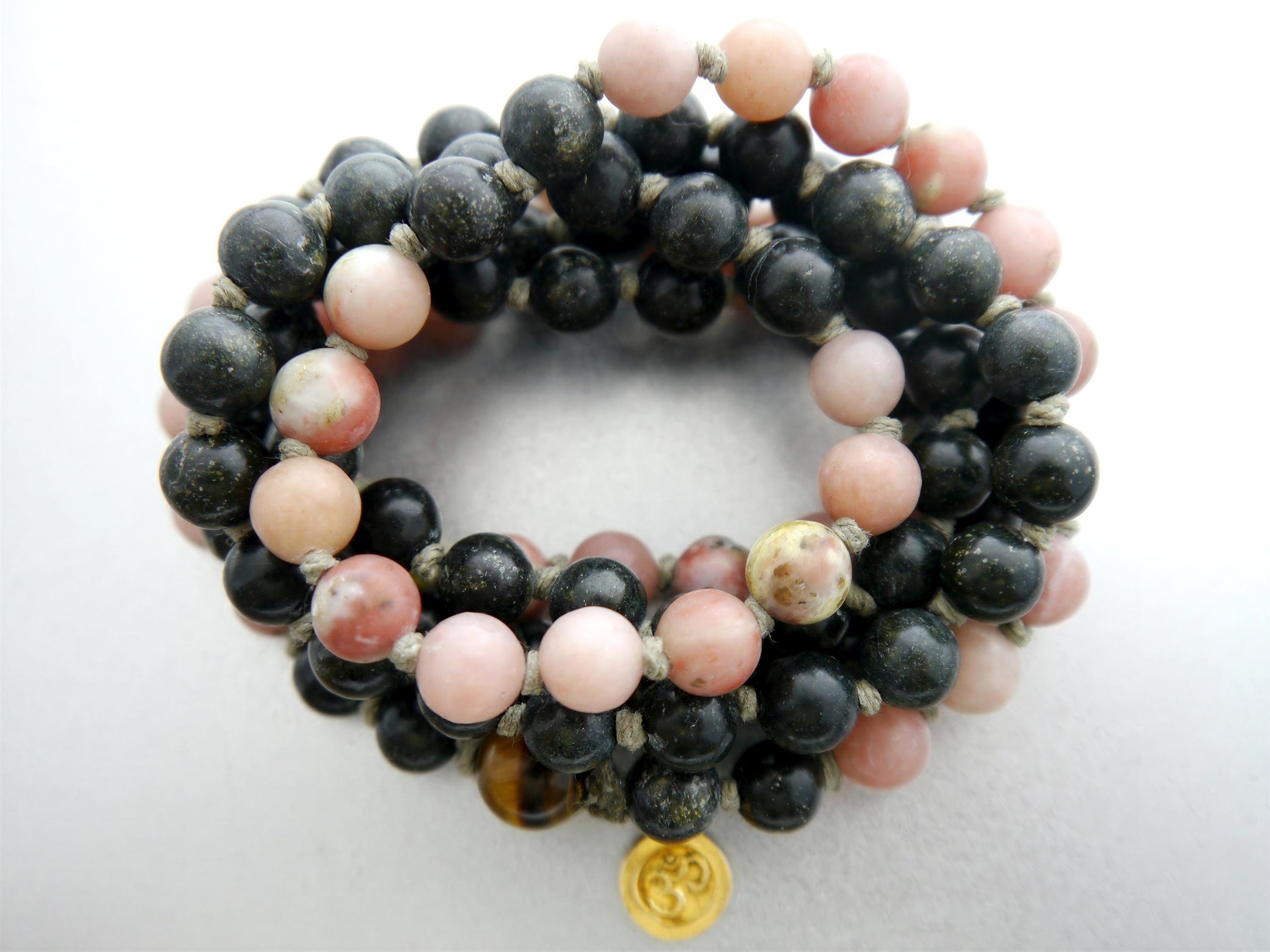 A close-up image of a bracelet made of beads in various colors, including black, pink, and brown.