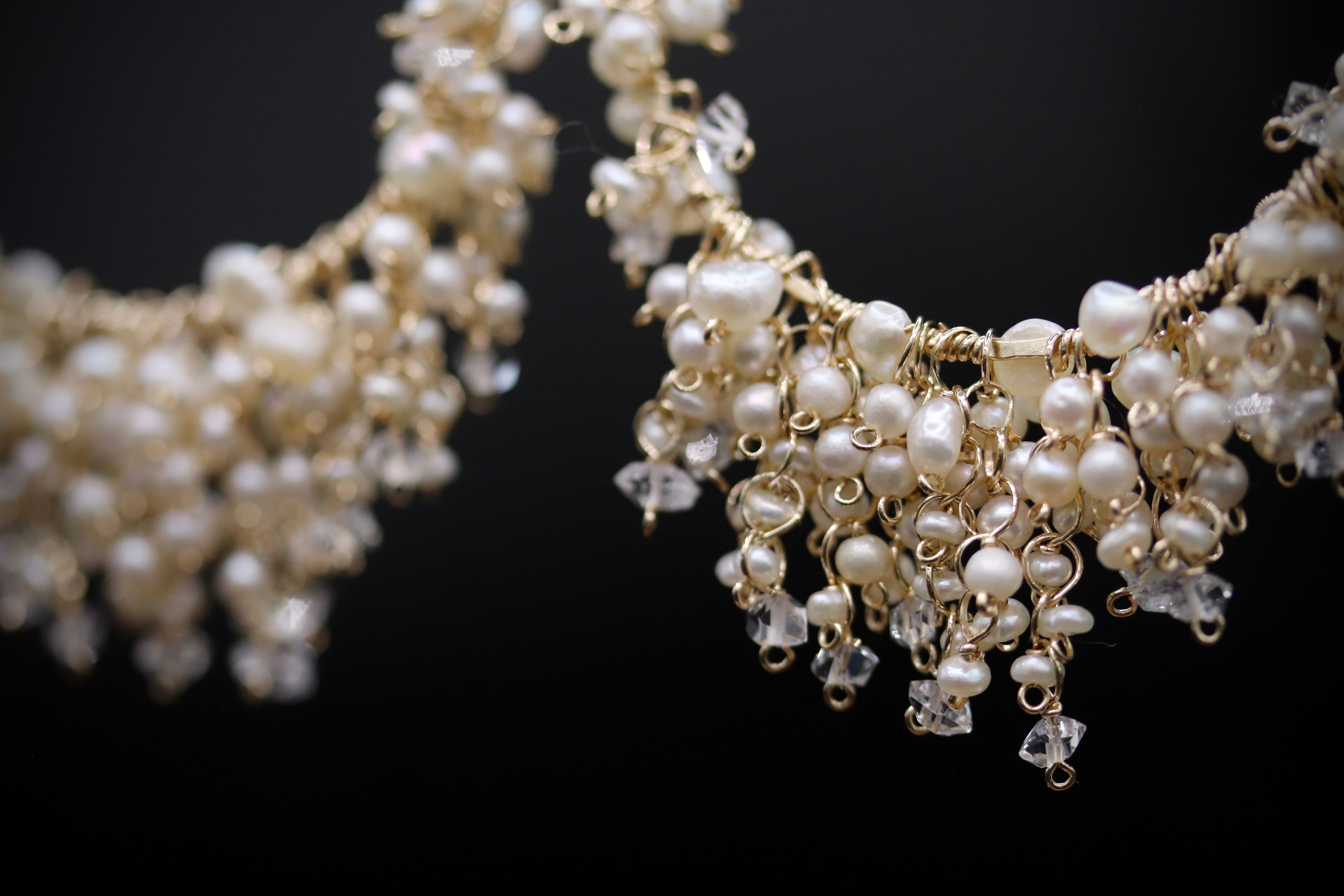 A close-up view of a delicate, ornate necklace with numerous small pearls and crystal-like embellishments.