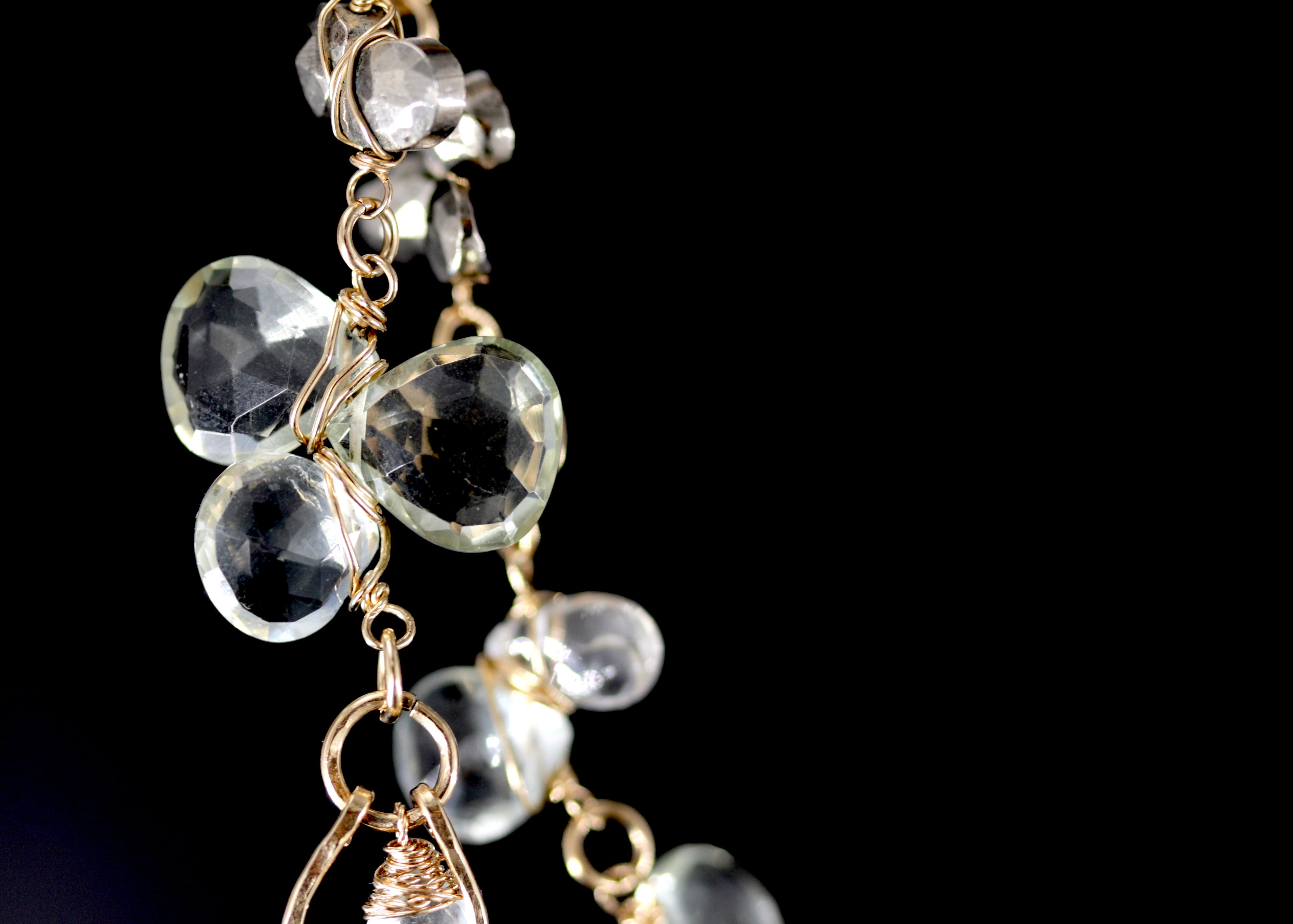 A close-up view of a delicate necklace with clear crystal pendants against a dark background.