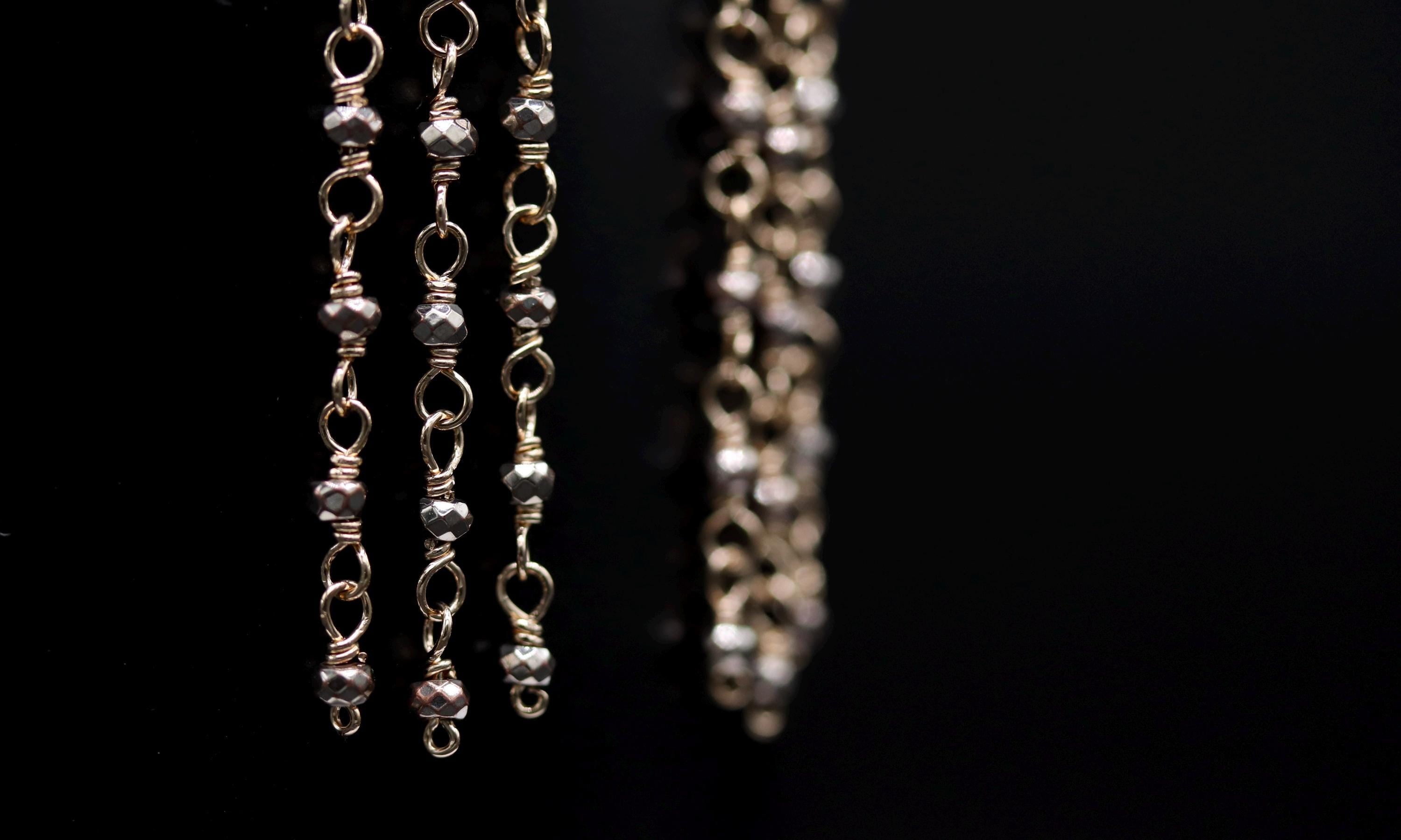 A close-up view of a pair of silver earrings with multiple strands of beads, creating a delicate and intricate design.