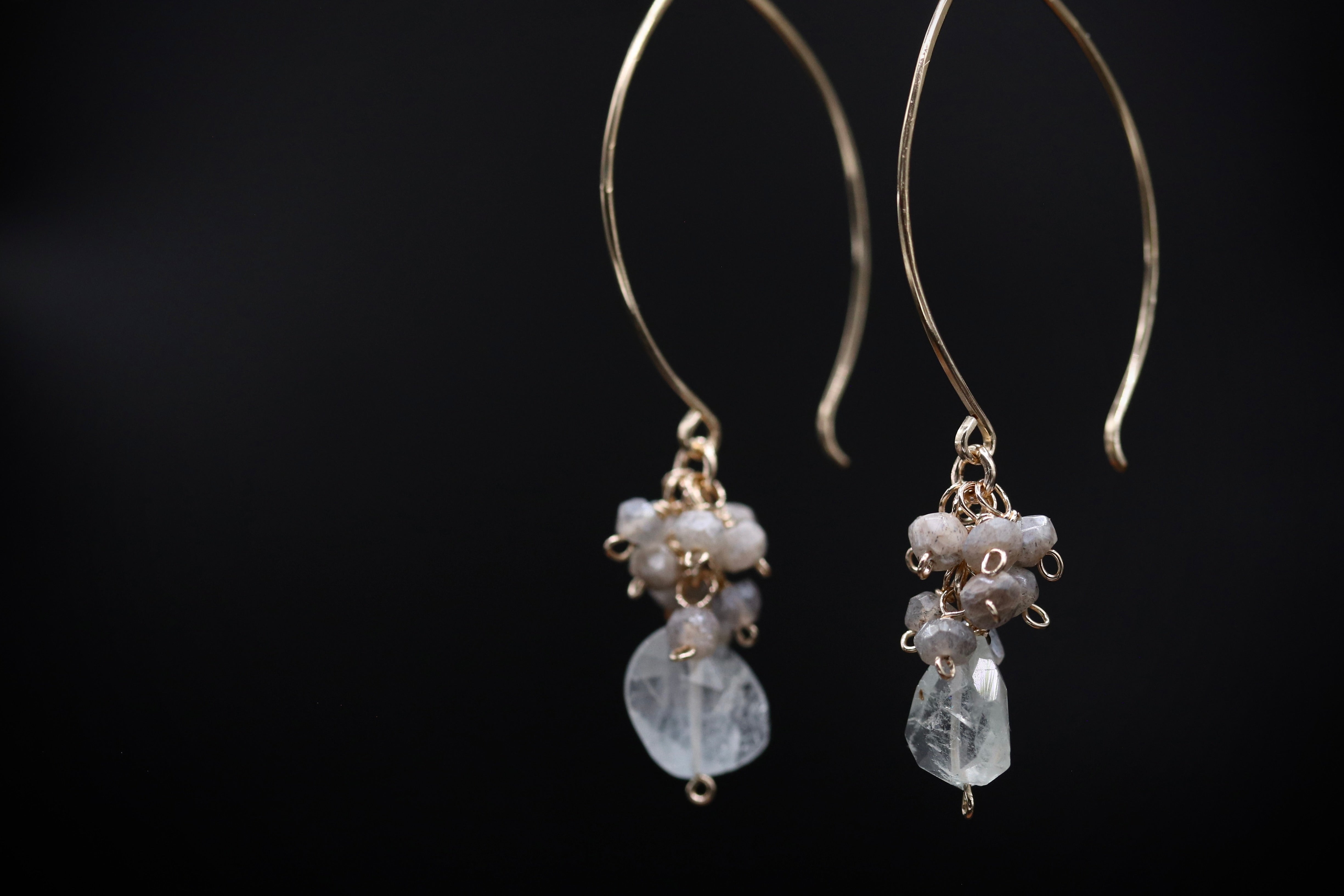 A pair of elegant earrings with clear gemstone accents and a delicate metal hook design.