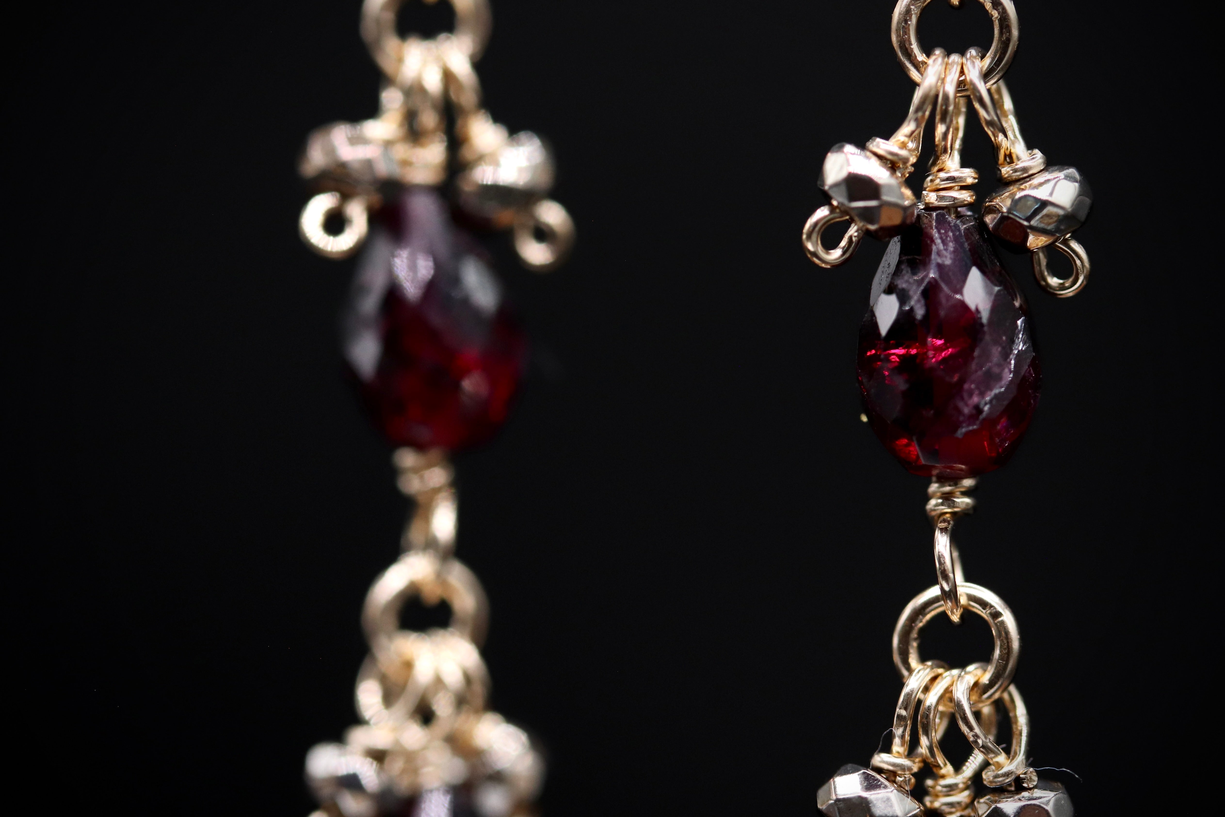 A close-up view of a pair of ornate earrings with red gemstones and intricate metalwork.
