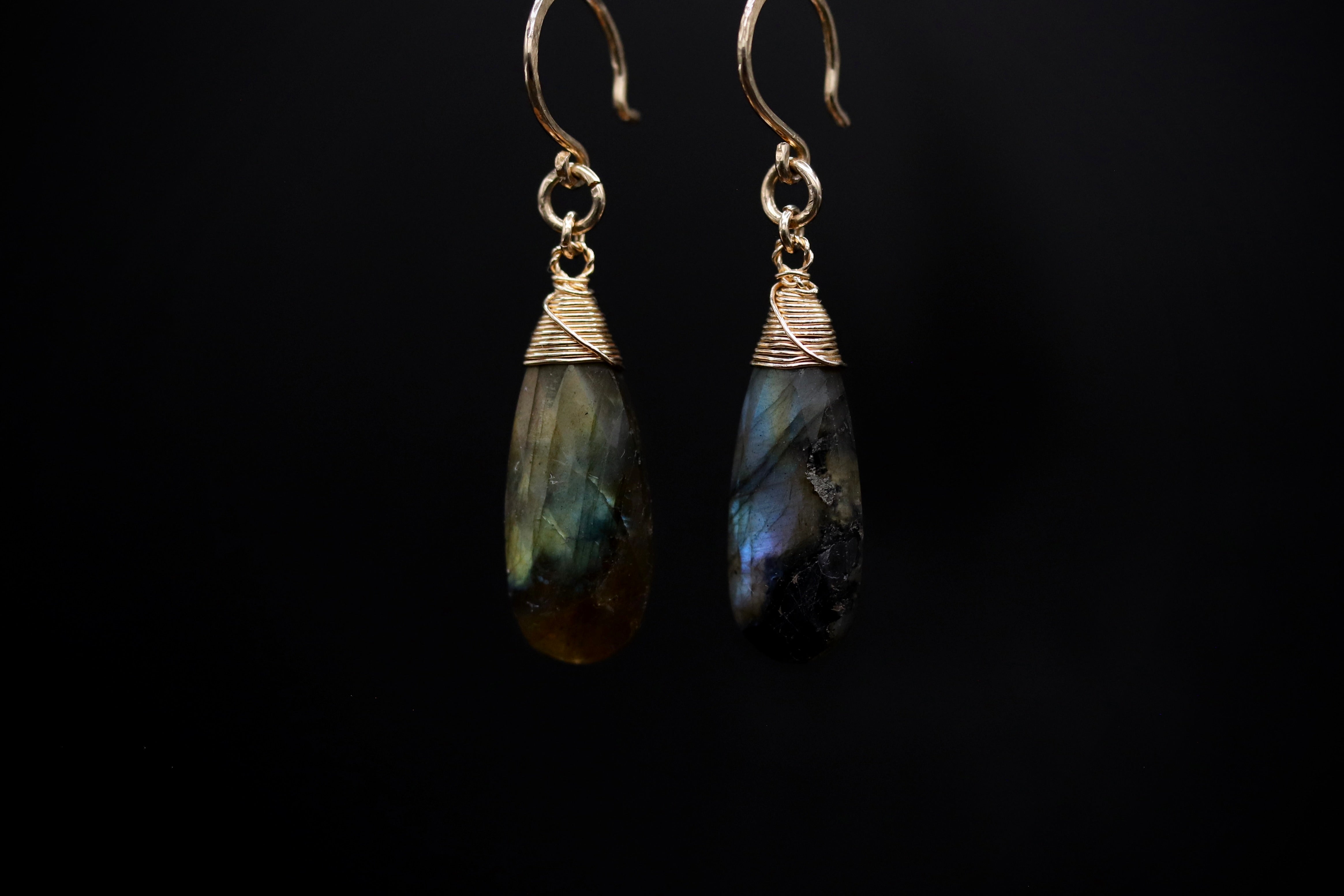 A pair of earrings with a dark background, featuring two dangling earrings with a unique, colorful stone or gemstone.