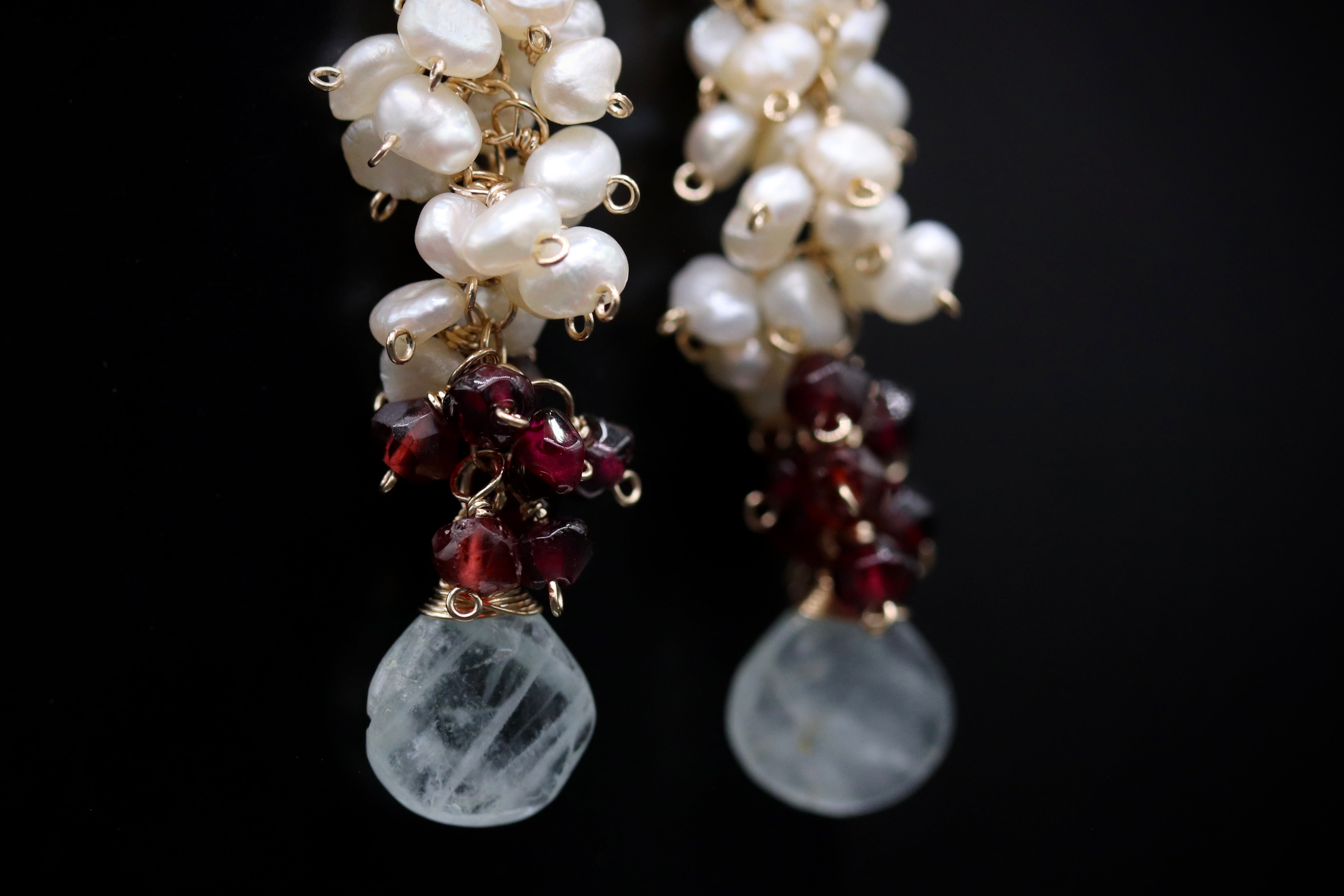 A pair of elegant earrings with white pearls and maroon gemstones.