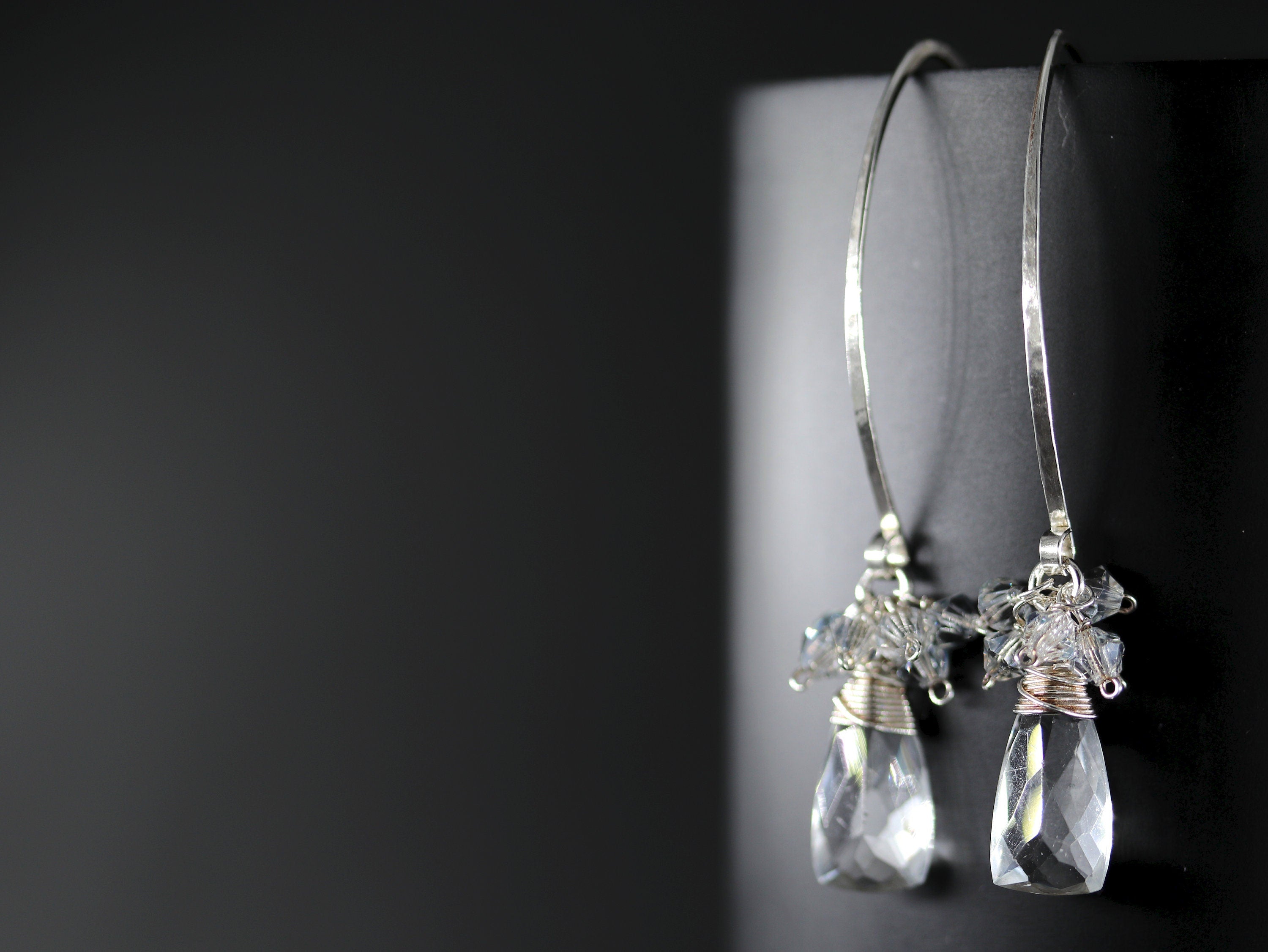 May include: Silver dangle earrings with clear teardrop crystals and smaller clear crystals clustered around the bottom of each teardrop.