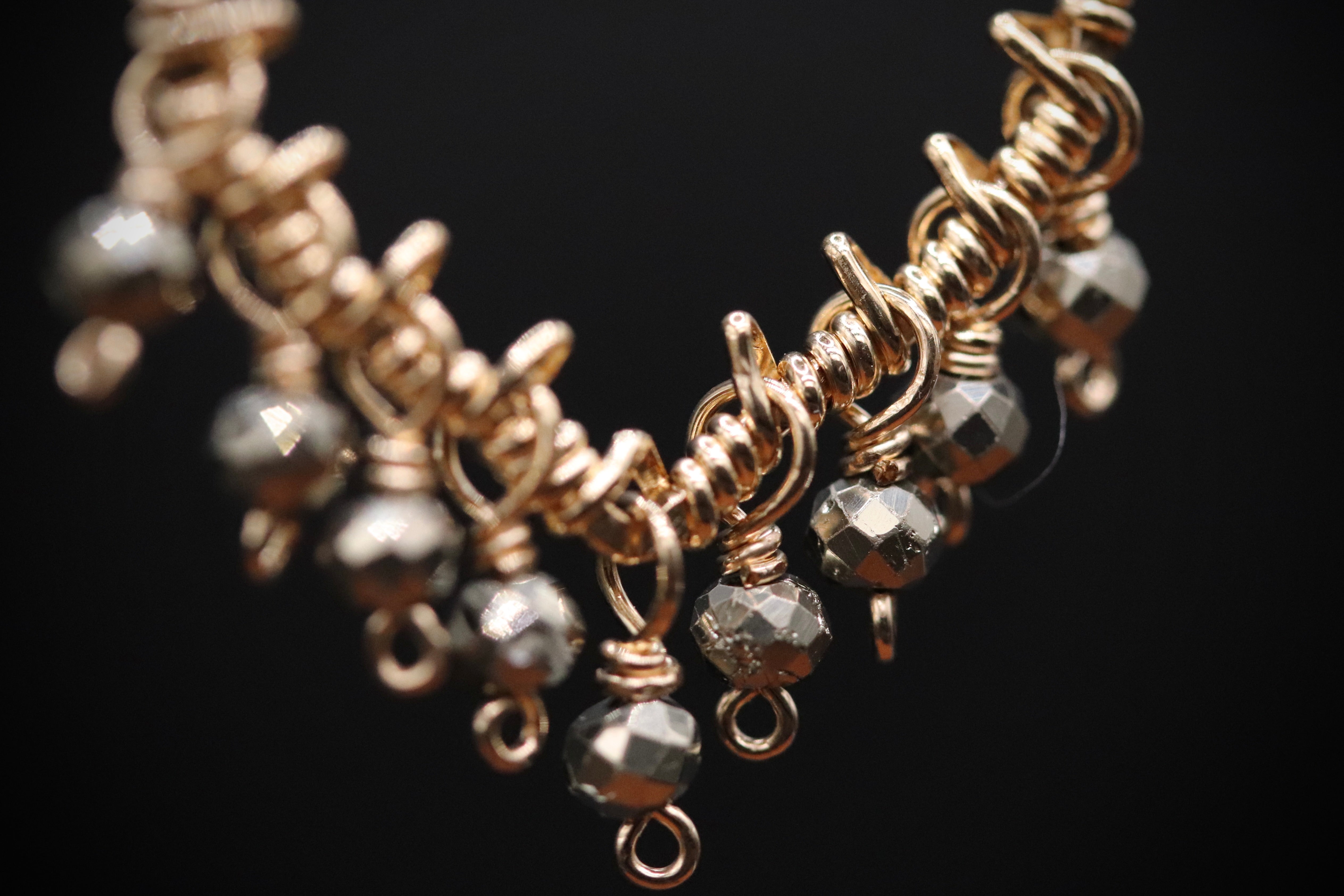 A close-up view of a gold-colored necklace with numerous small, dangling beads.