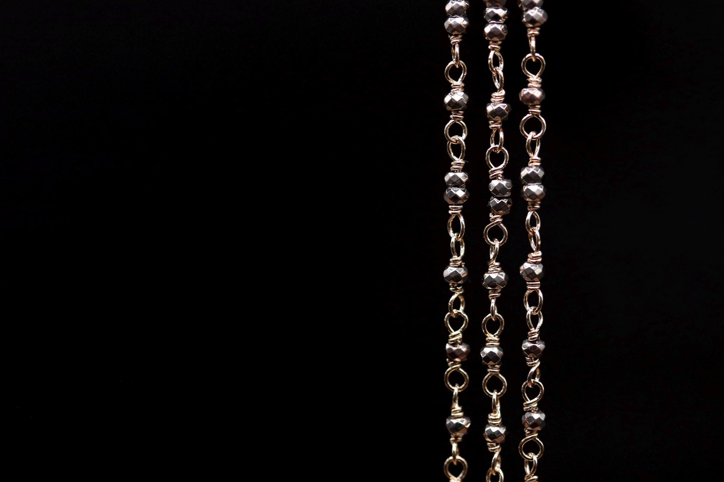 A close-up view of a chain with multiple links, showcasing the intricate design and texture of the metal beads.