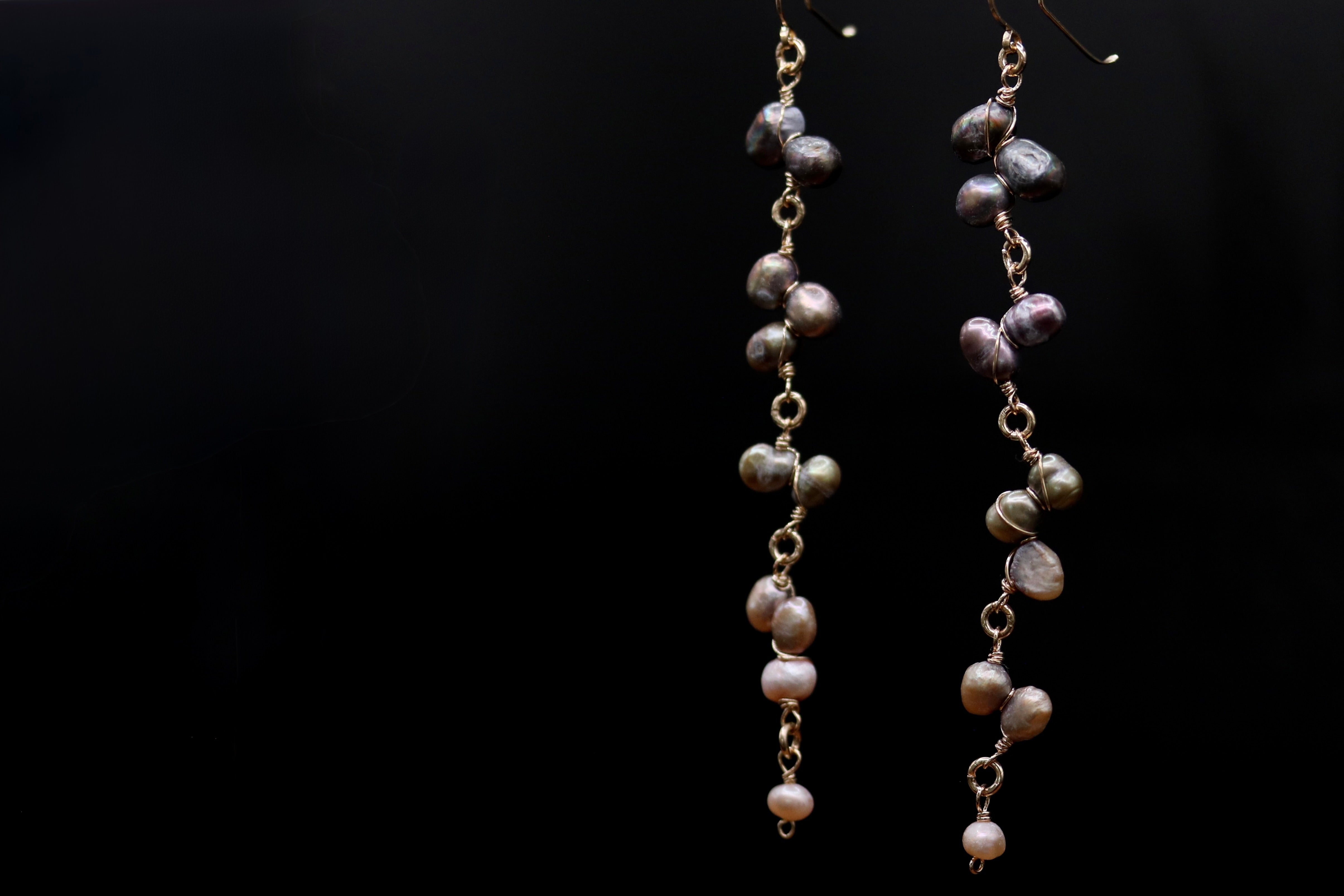 A pair of elegant earrings made of small, round pearls suspended from a chain, creating a delicate and sophisticated design.