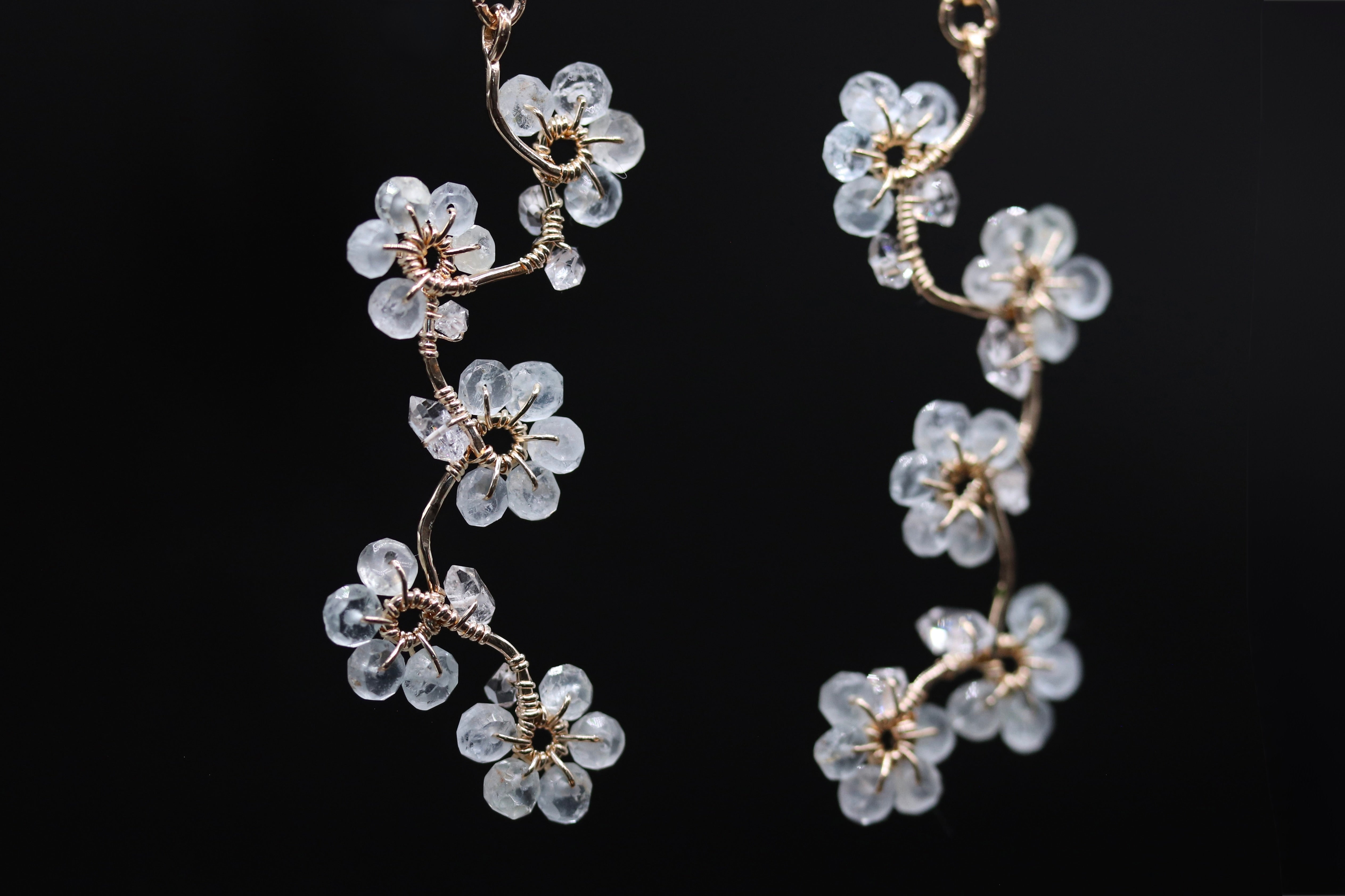 A pair of delicate earrings with clear crystal flowers on a black background.