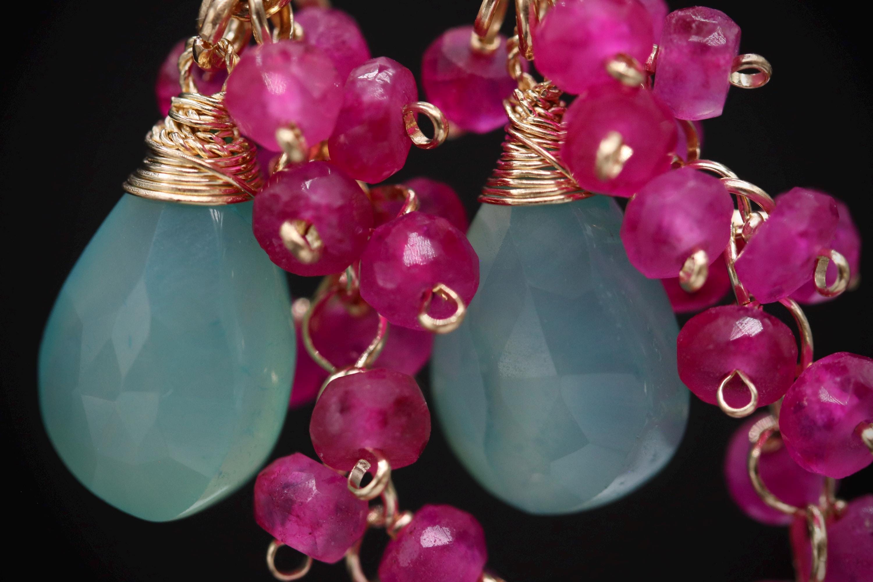 A close-up image of a pair of earrings with turquoise stones and pink beads.