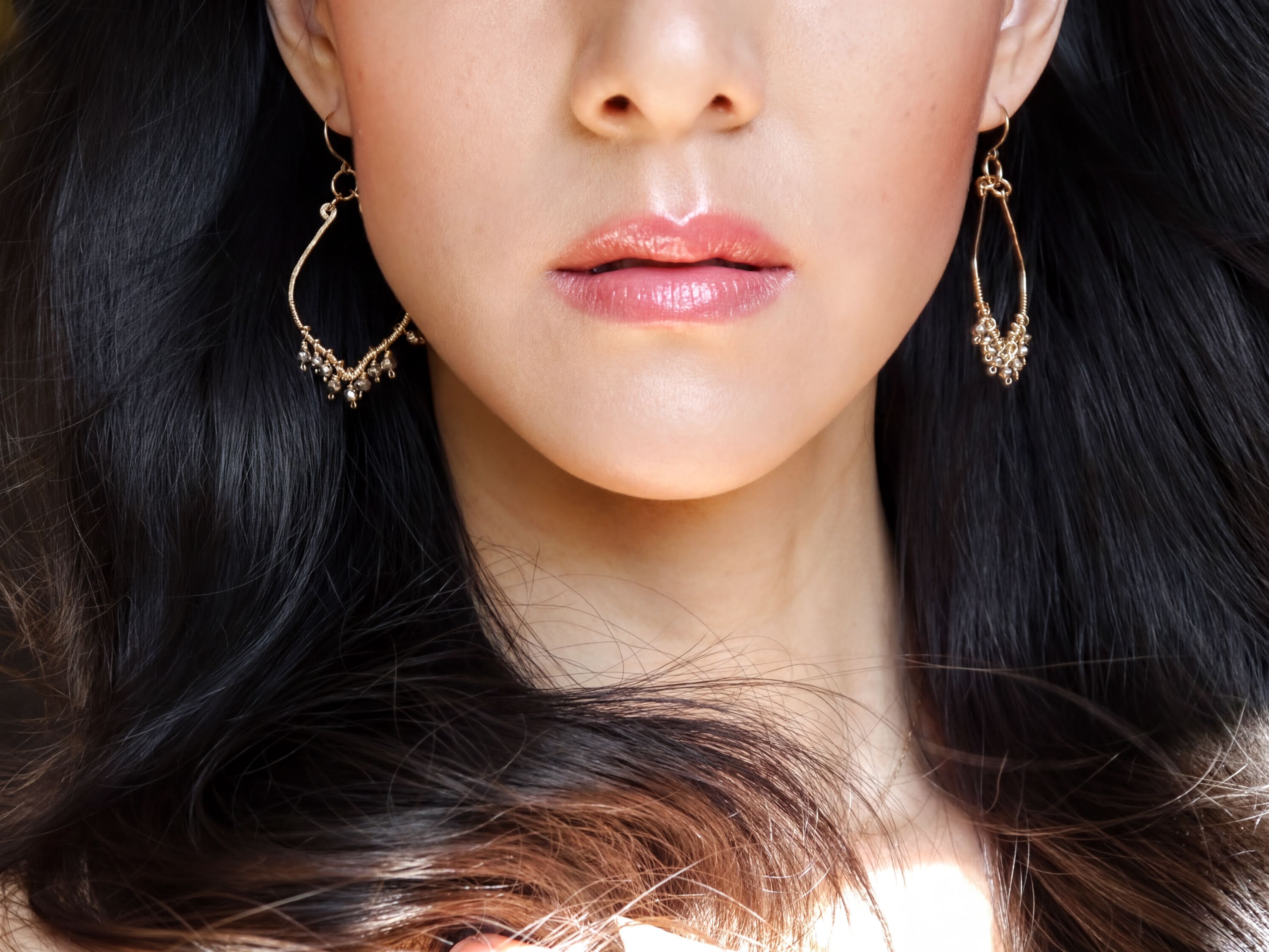 A close-up of a woman's face, focusing on her earrings and hair.
