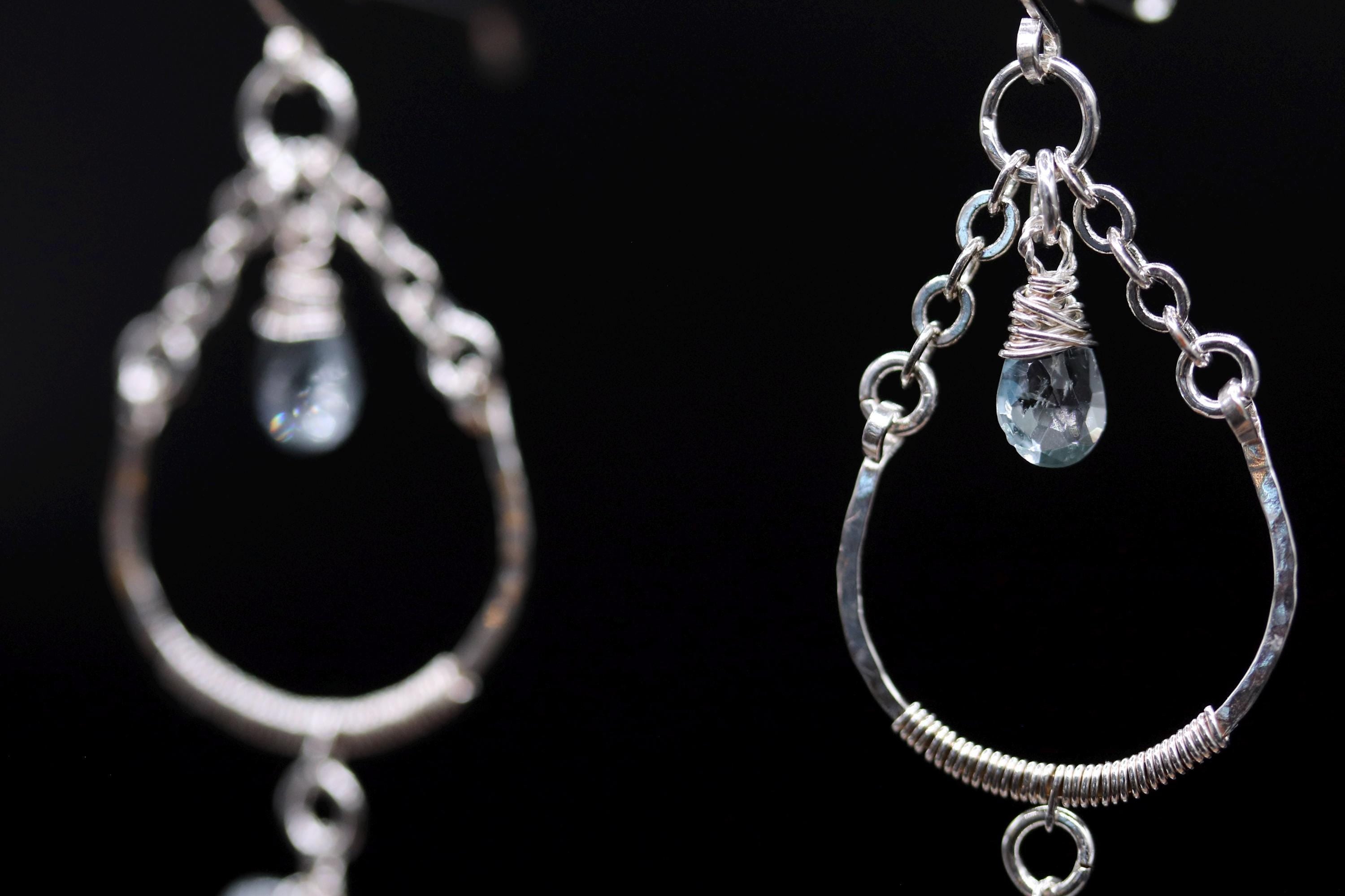 A pair of silver earrings with clear gemstones hanging from the chains.