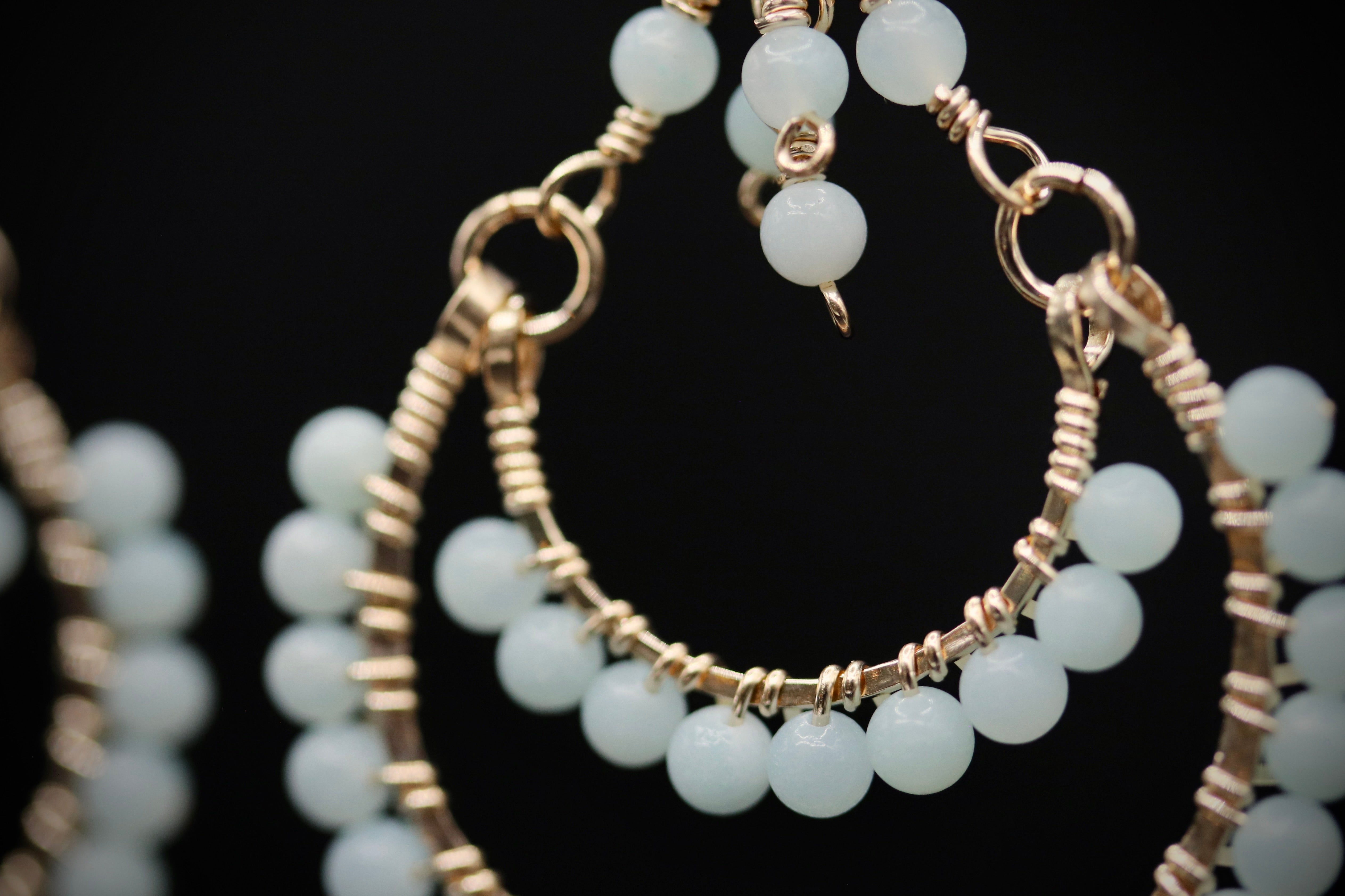 A close-up view of a pair of gold-colored earrings with white beads, showcasing the intricate design and craftsmanship.