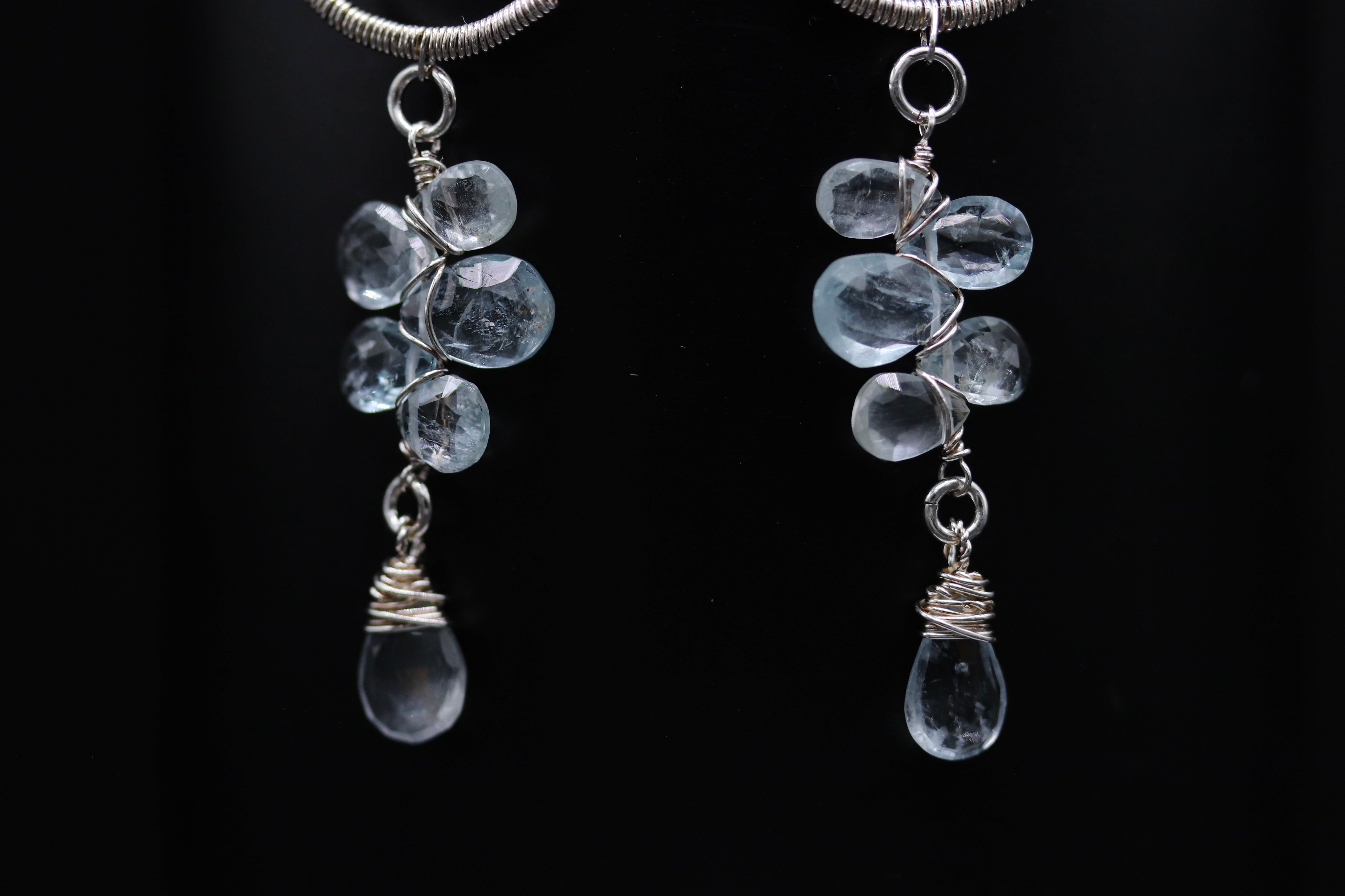 A pair of elegant earrings with clear crystal stones hanging from a wire.