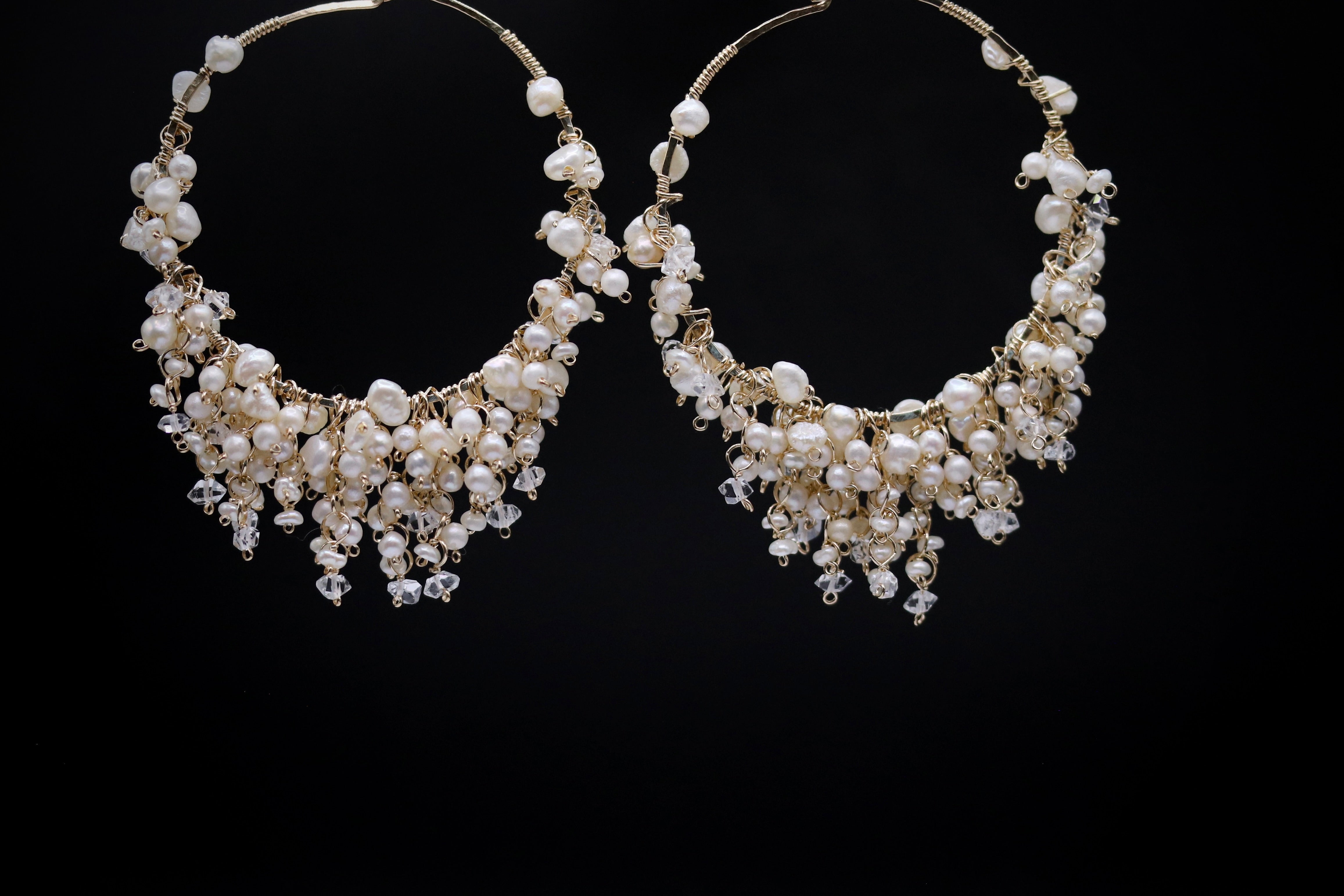 A pair of elegant earrings with a delicate design, featuring numerous small pearls and crystals that drape down the sides, creating a cascading effect.