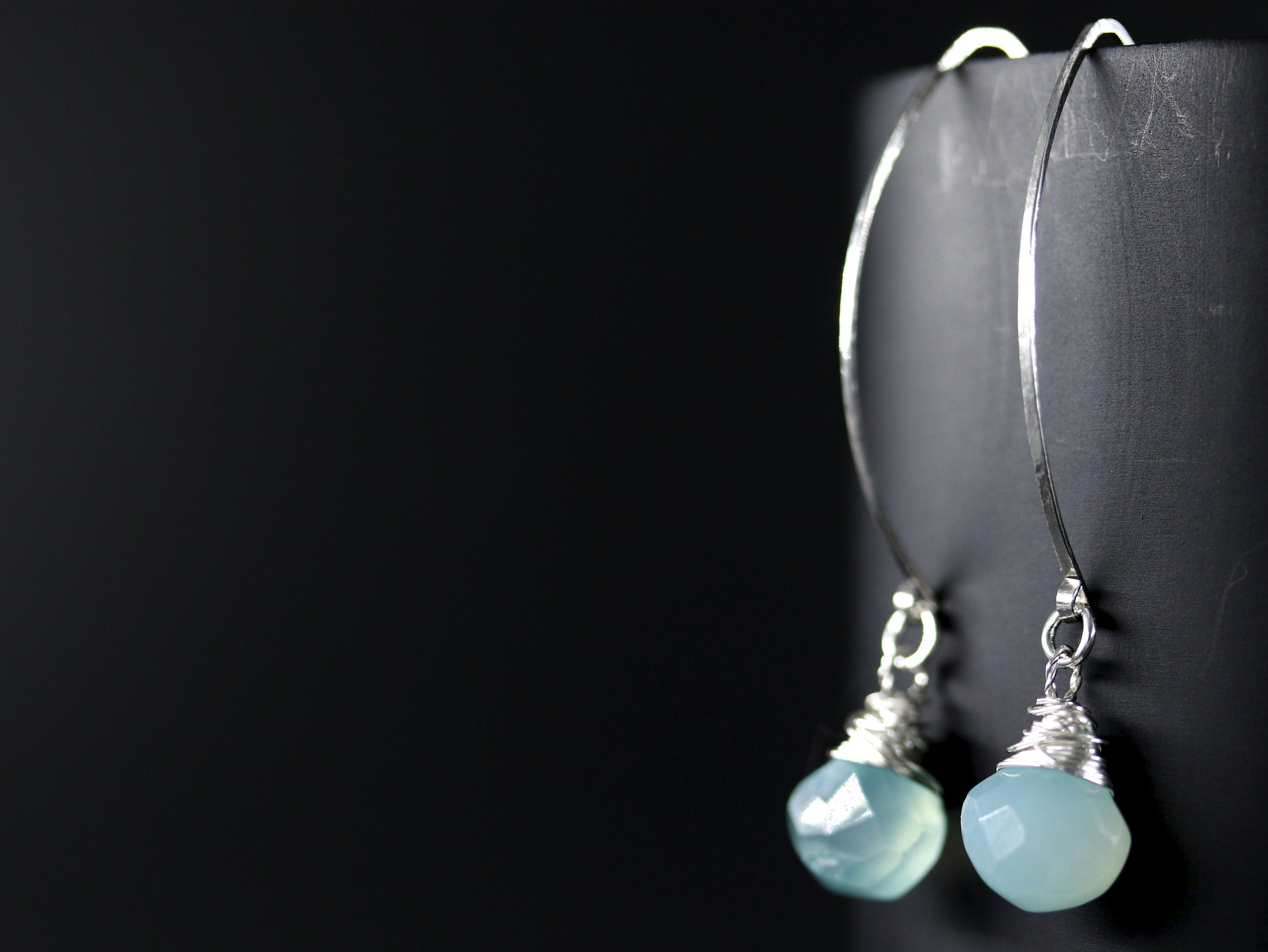 May include: A pair of silver dangle earrings with light blue gemstone drops.