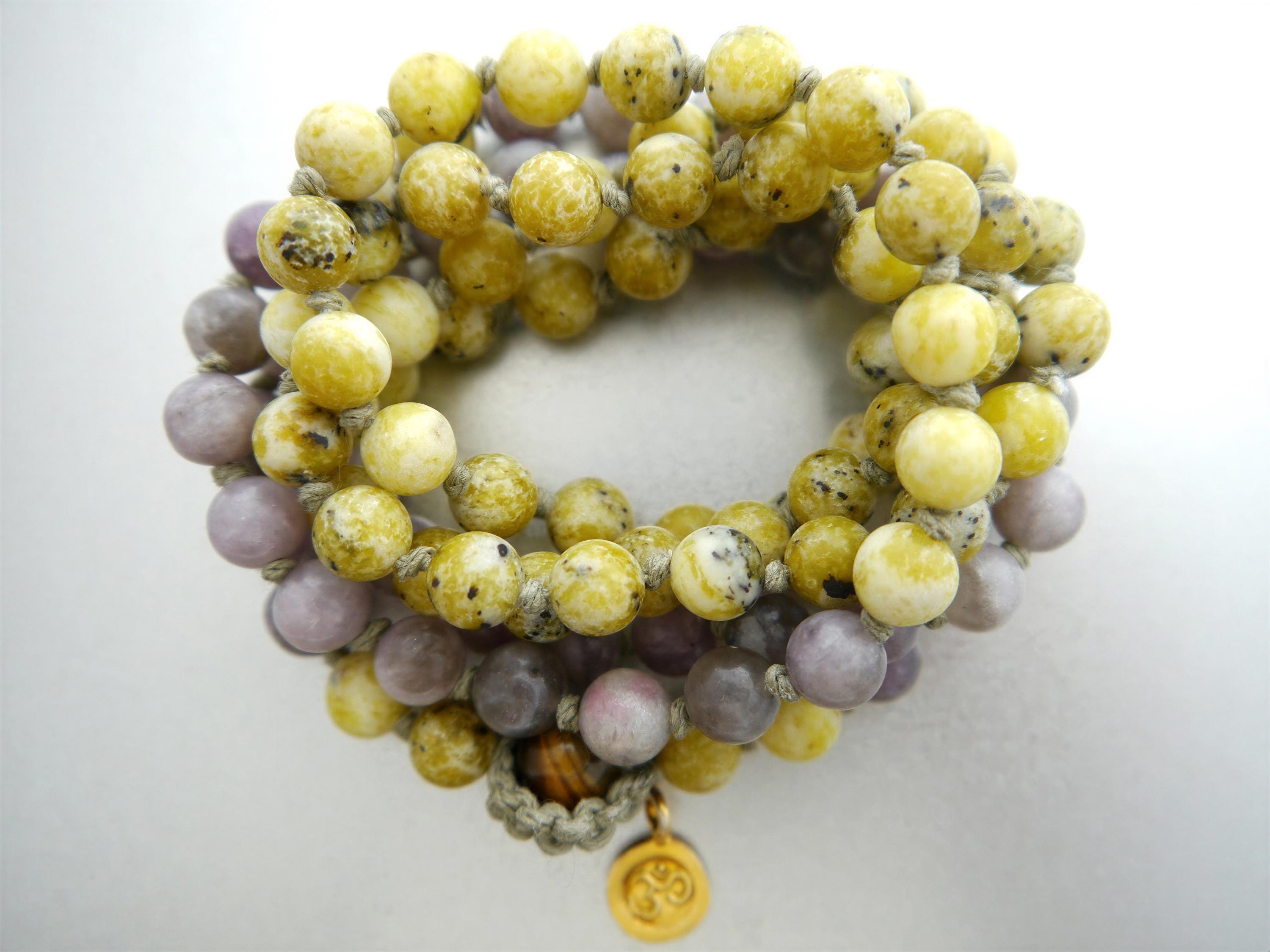 A beaded bracelet with yellow and purple beads, featuring a charm at the center.