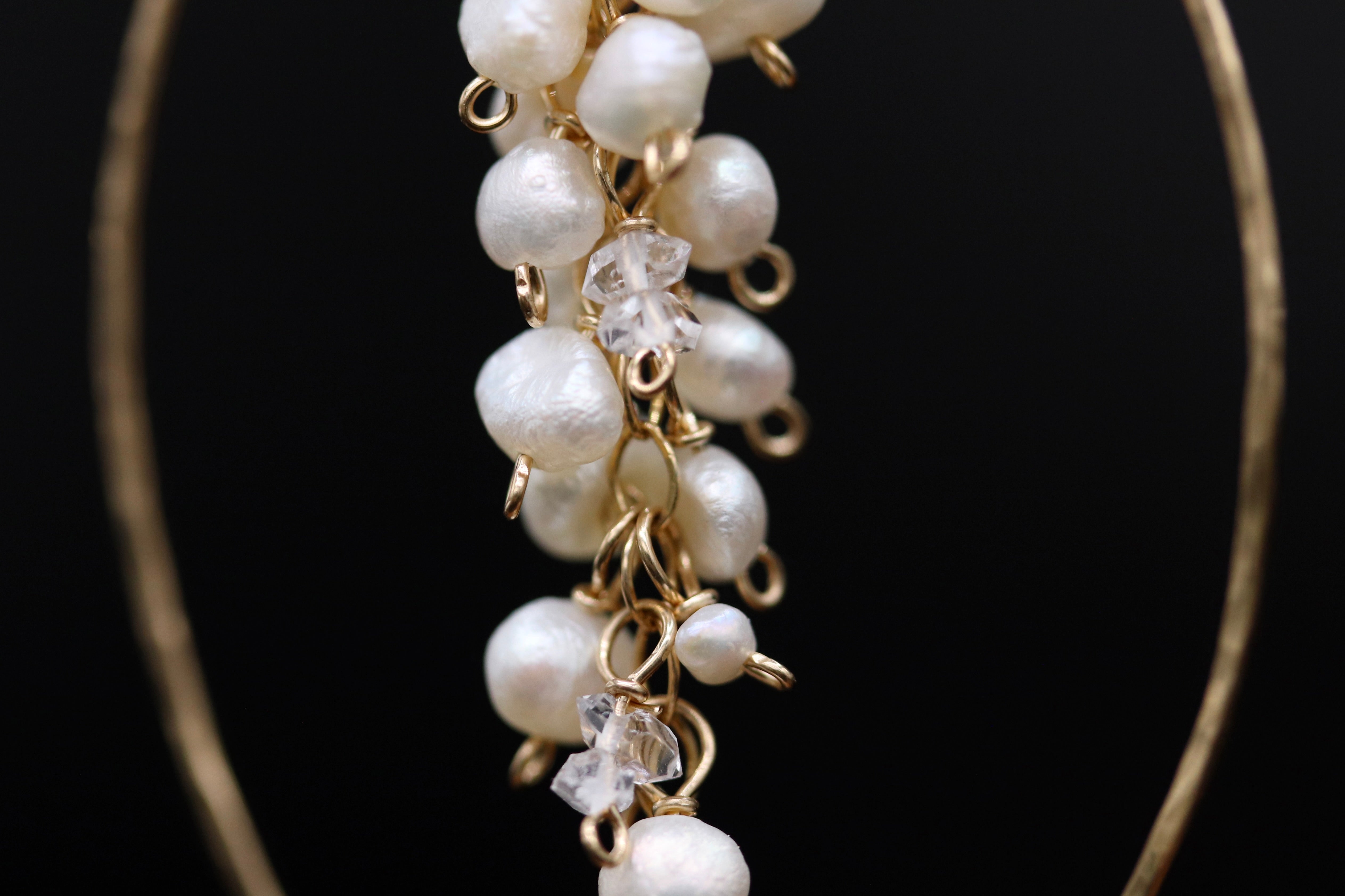 A close-up view of a delicate gold earring with a cluster of white pearls and clear stones.