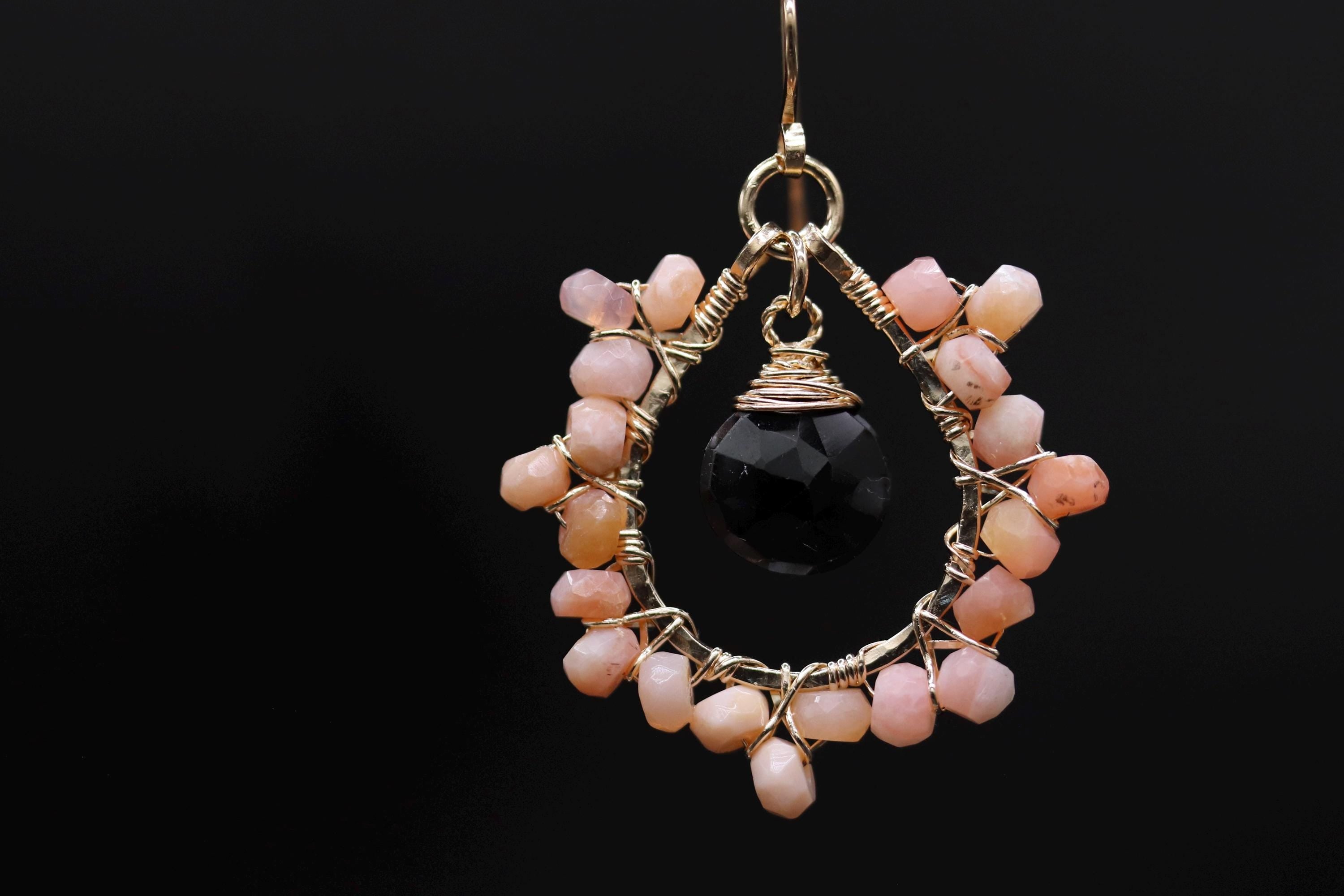A close-up view of a decorative earring with a black gemstone and a cluster of pink and white stones.