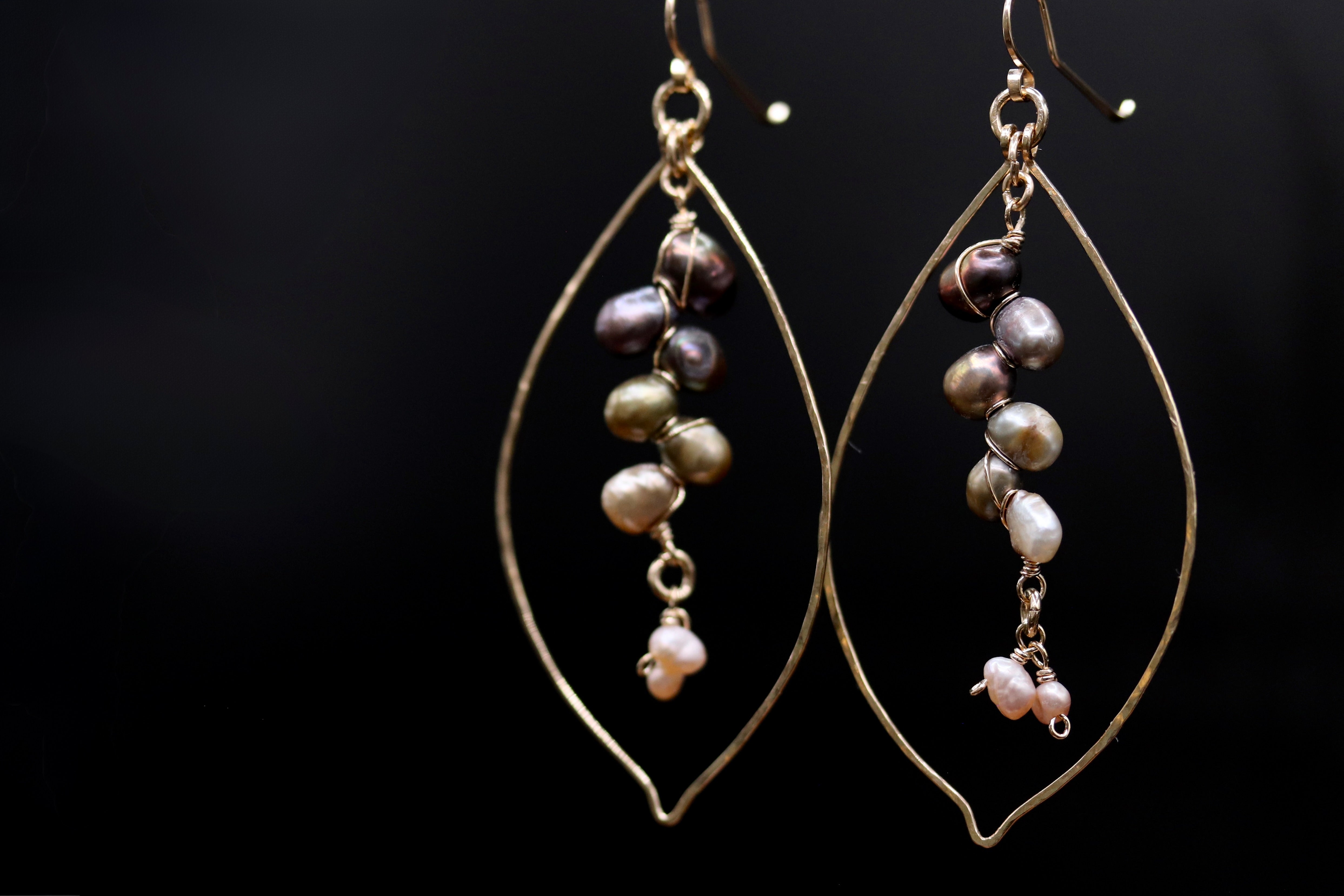 A pair of elegant earrings with a leaf-shaped design, featuring a series of pearls hanging from the center.