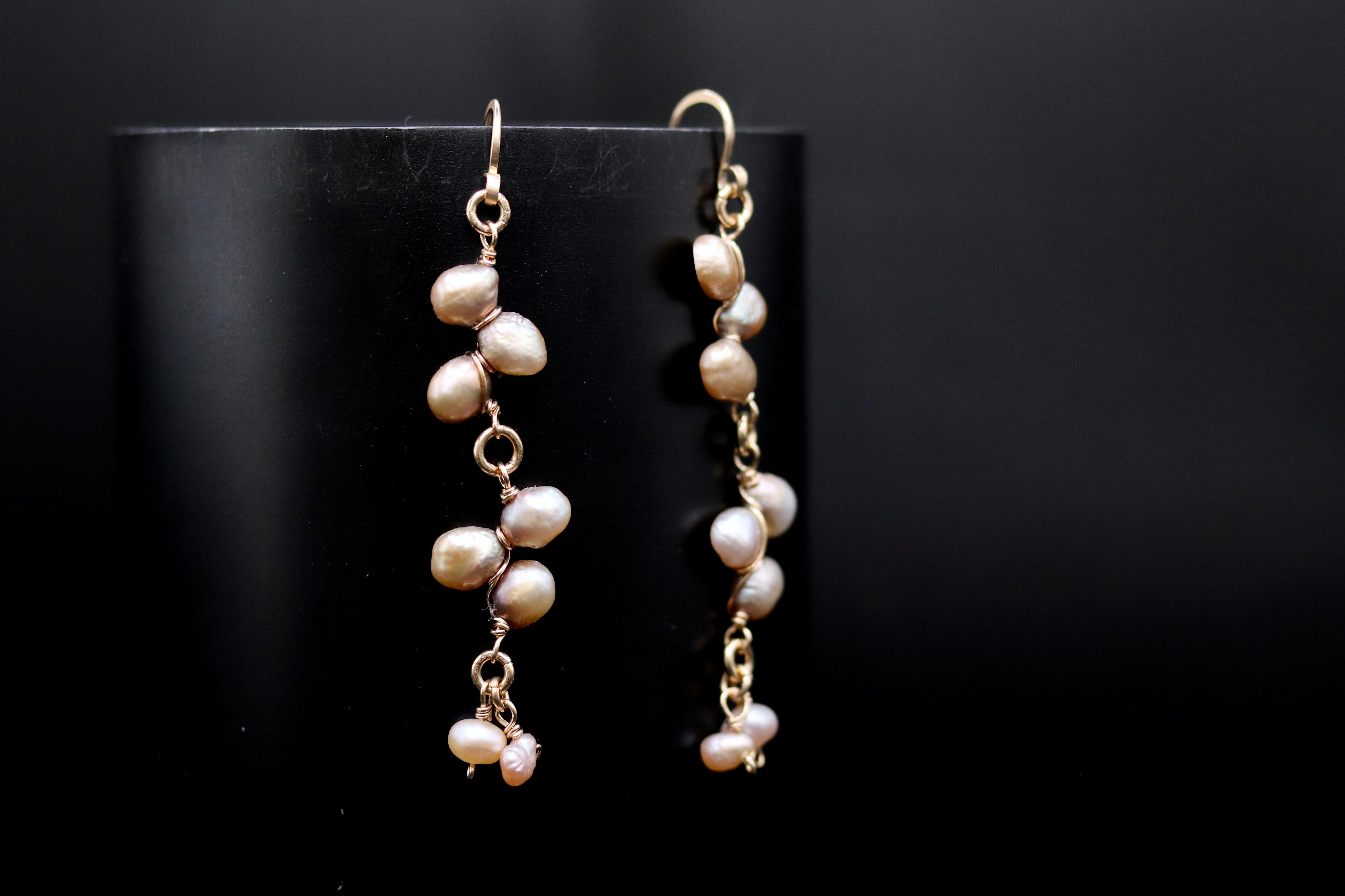 A pair of elegant earrings with a row of small pearls hanging from the bottom, set against a dark background.